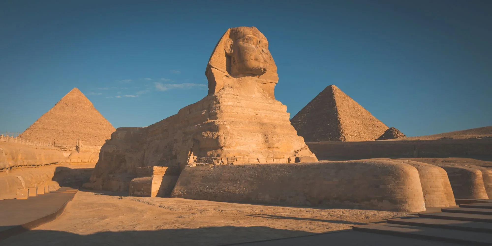 A wide view of the Great Sphinx and Pyramids of Giza, showcasing the ancient monuments free from site congestion.