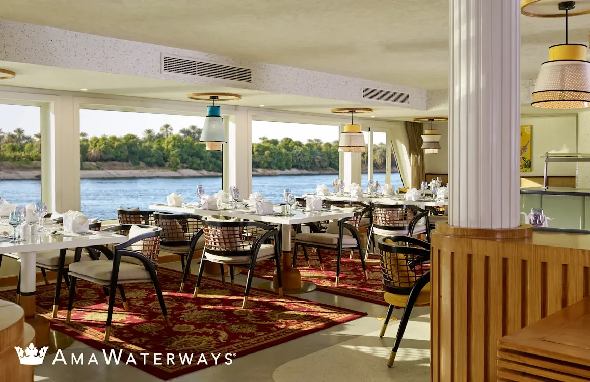 The sophisticated main dining room aboard the AmaWaterways AmaDahlia, featuring elegant decor and expansive panoramic windows that offer immersive river views during the voyage.