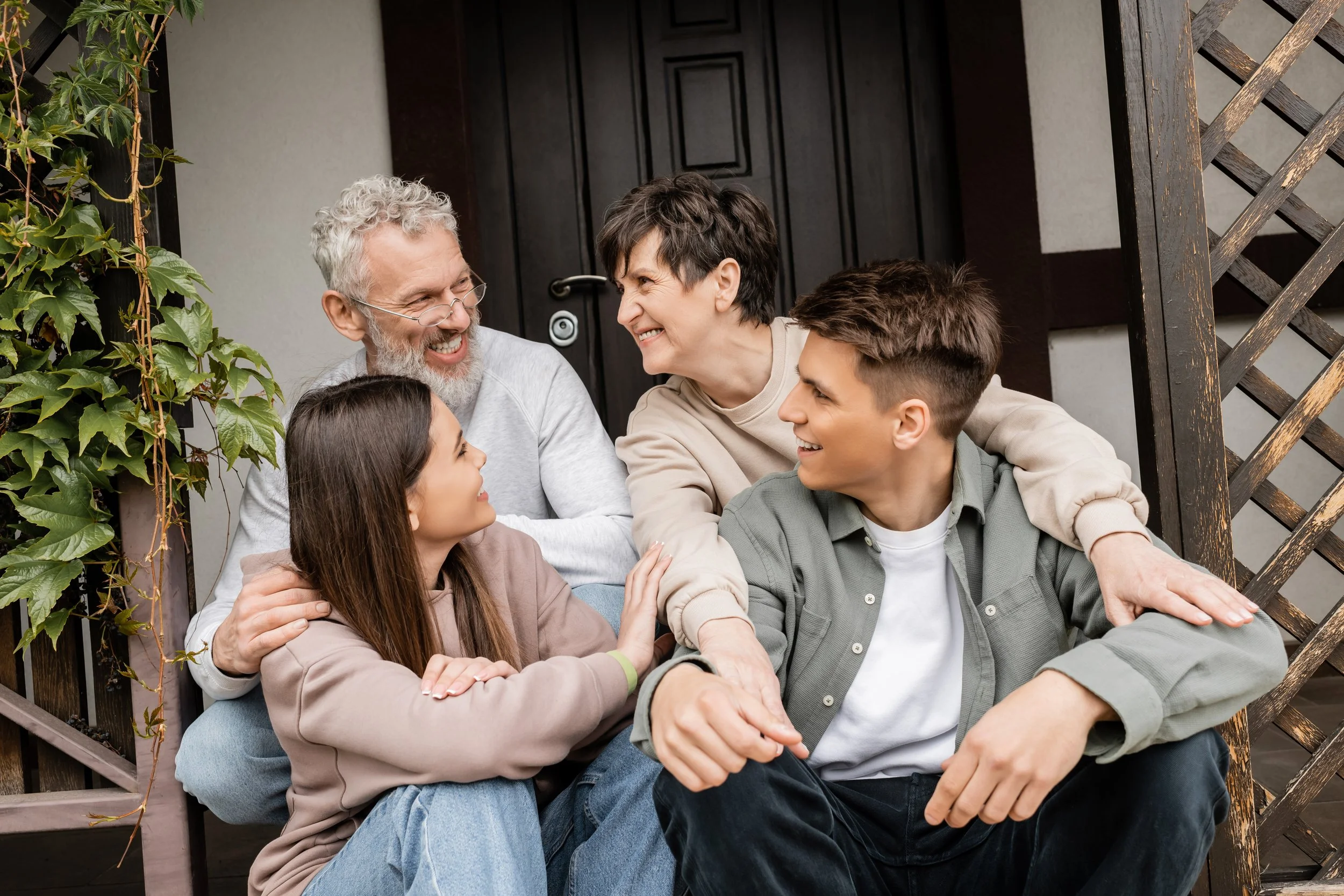 A family of five sitting on a porch, smiling and enjoying each other's company.