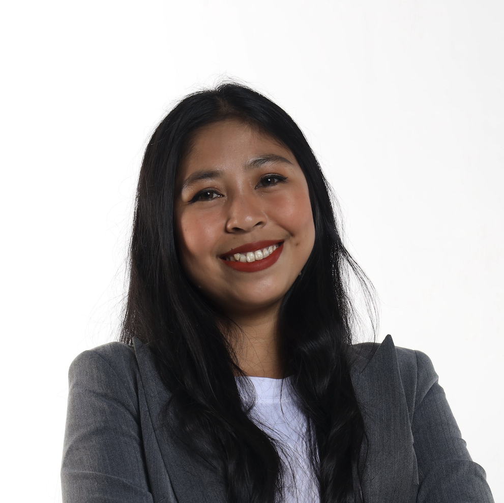 A young woman with long black hair, wearing a dark gray blazer and white shirt, smiling against a white background.