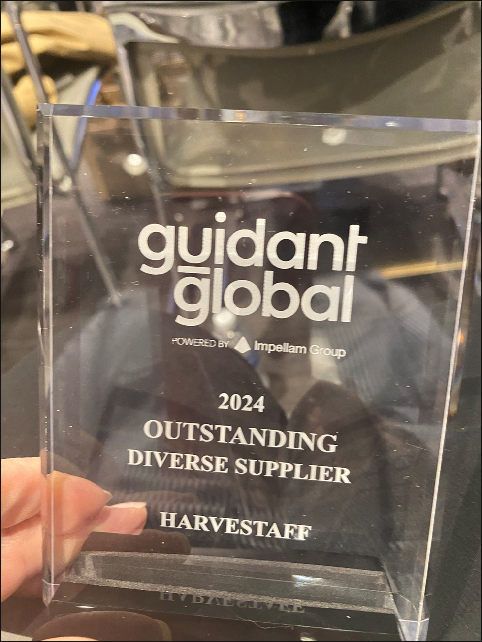 A clear acrylic award plaque with white text, recognizing Harvestaffe as an outstanding diverse supplier in 2024, presented by Guidant Global and Impellam Group.