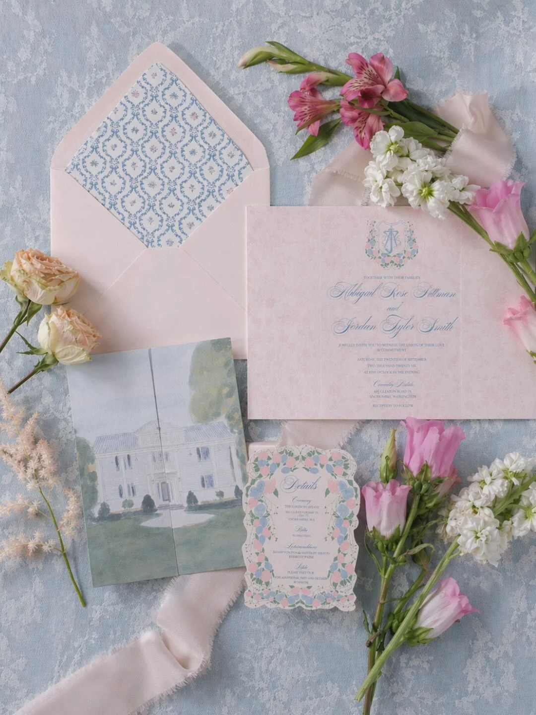 A soft blue and blush wedding invitation suite designed to feel romantic, feminine, and completely personal.

This custom stationery collection included a bespoke wedding crest, hand-painted venue illustration, patterned envelope liner, floral detail