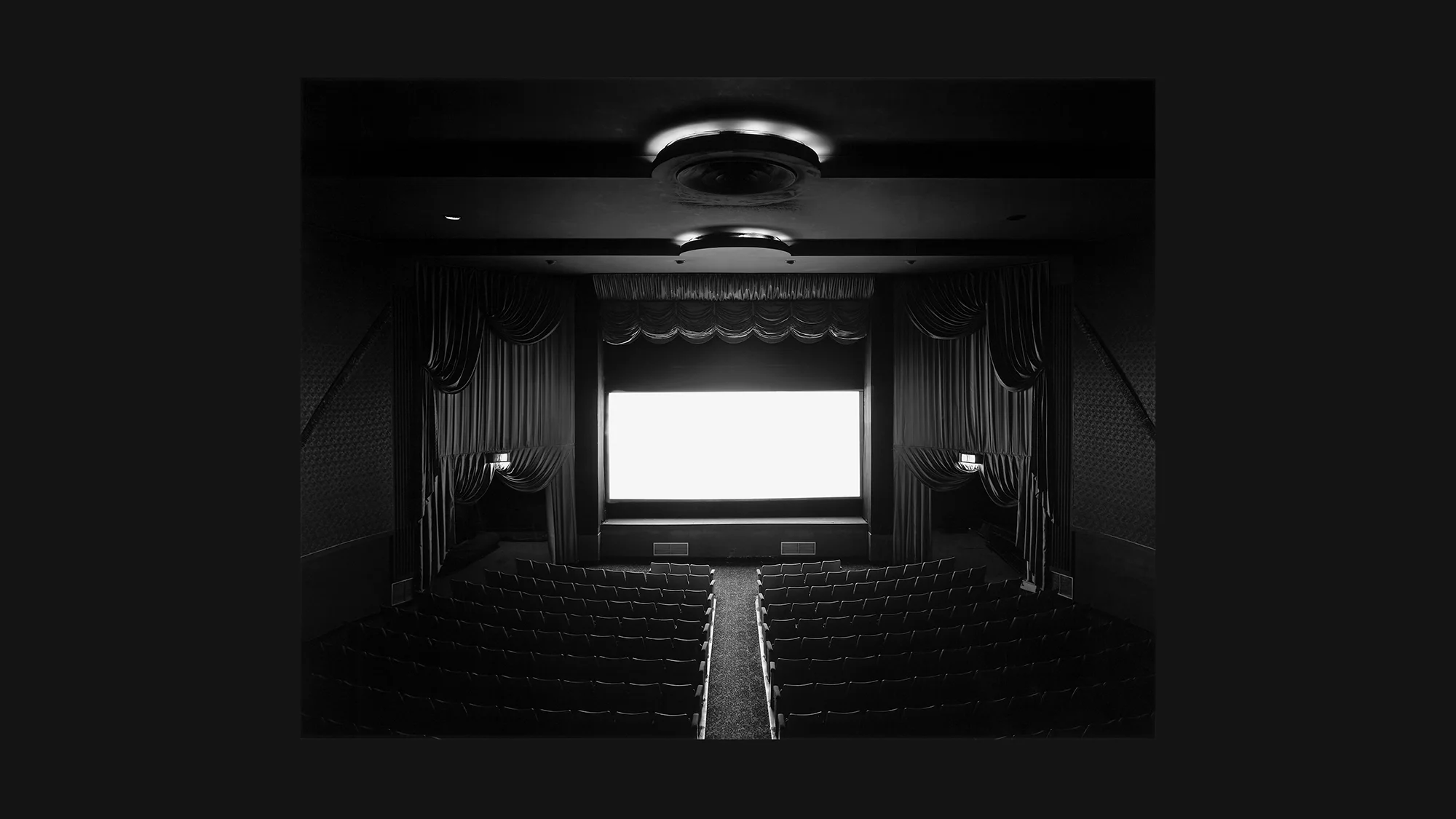 Sugimoto 1977: glowing white cinema screen surrounded by dark theatre interior – full-length film exposure captured as a single image