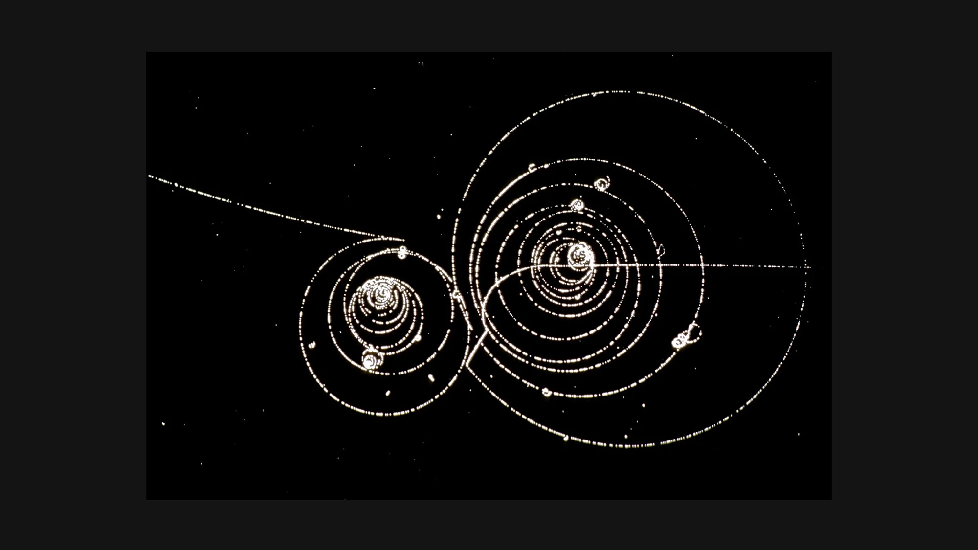 CERN 1973: Subatomic particle tracks in liquid hydrogen bubble chamber – kaon decay and omega production visible as curved bubble trails