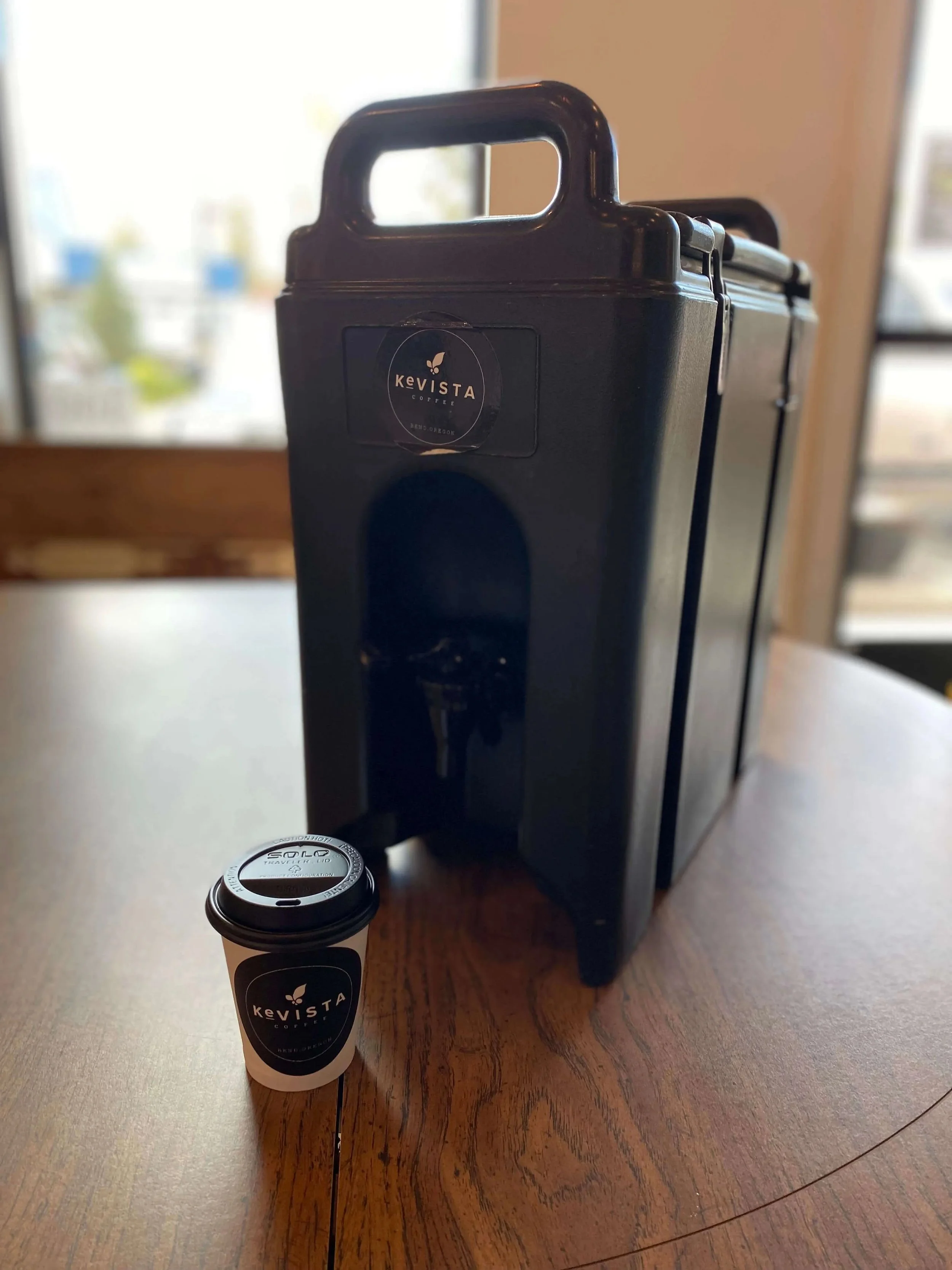 Coffee carafe and cup on table with "Kevista Coffee" branding.