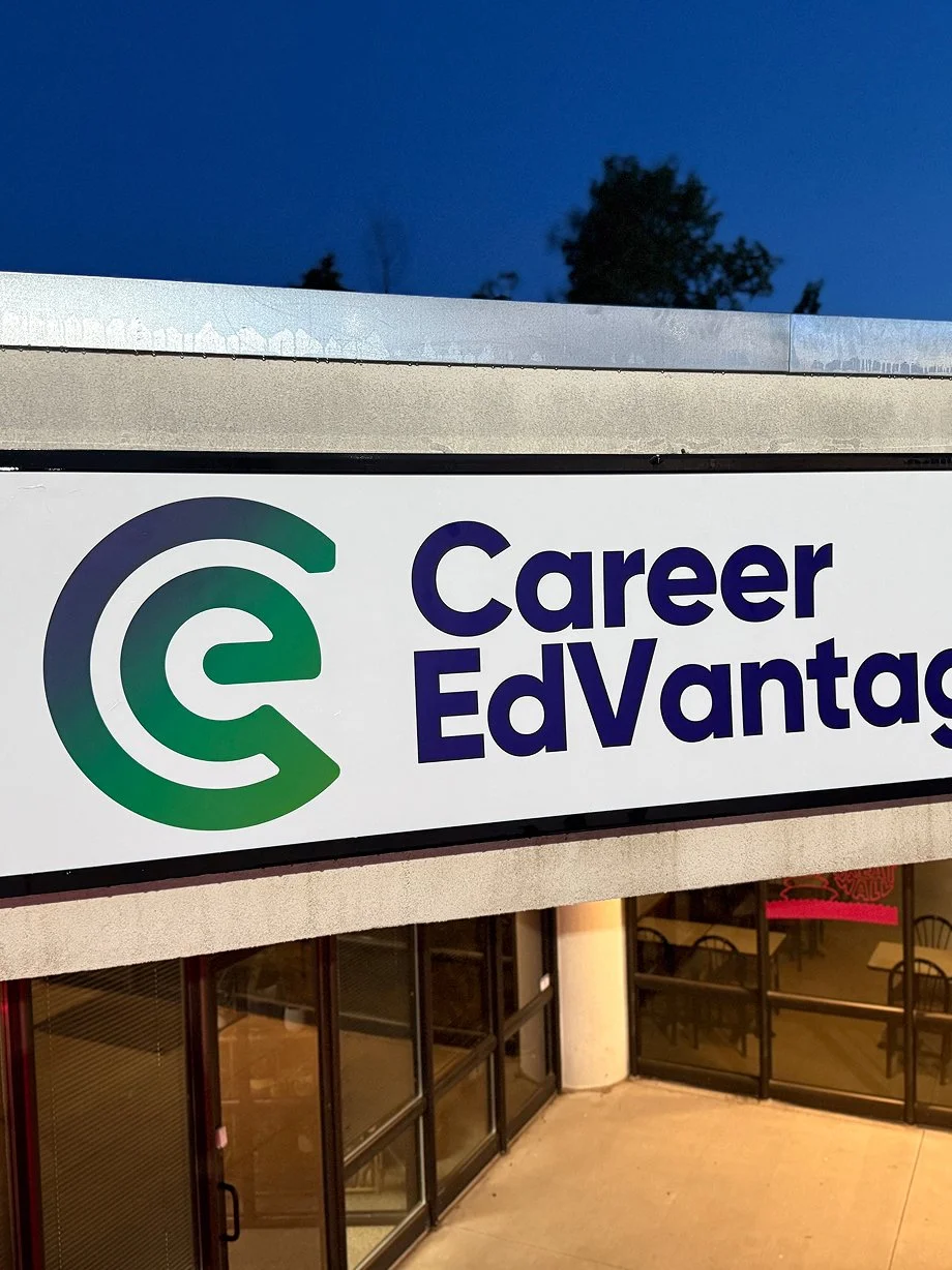 Sign reading 'Career EdVantages' with a logo, outside a building at dusk.