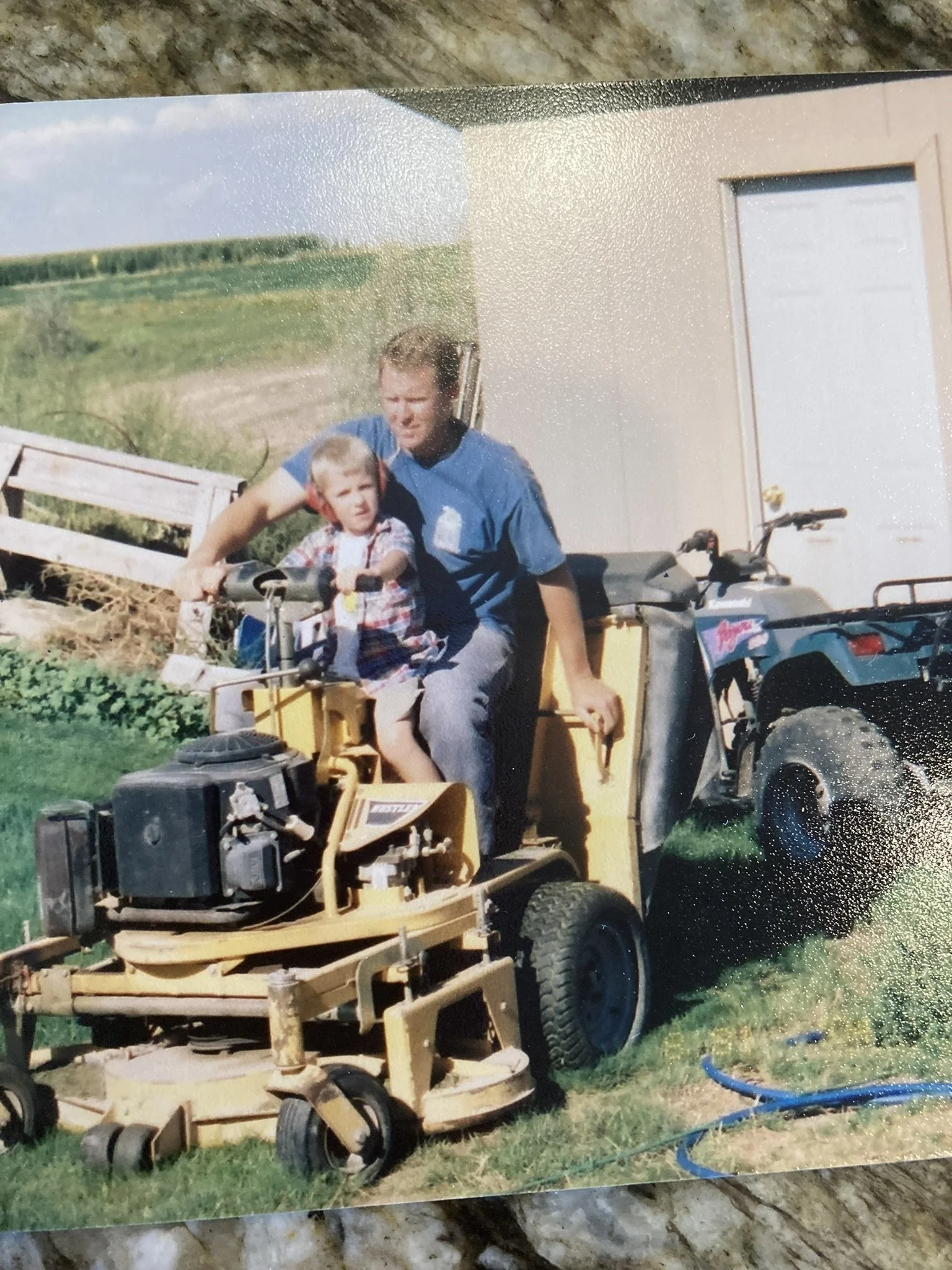 Childhood photo of Brett Nielsen riding a lawnmower with his father in rural Idaho