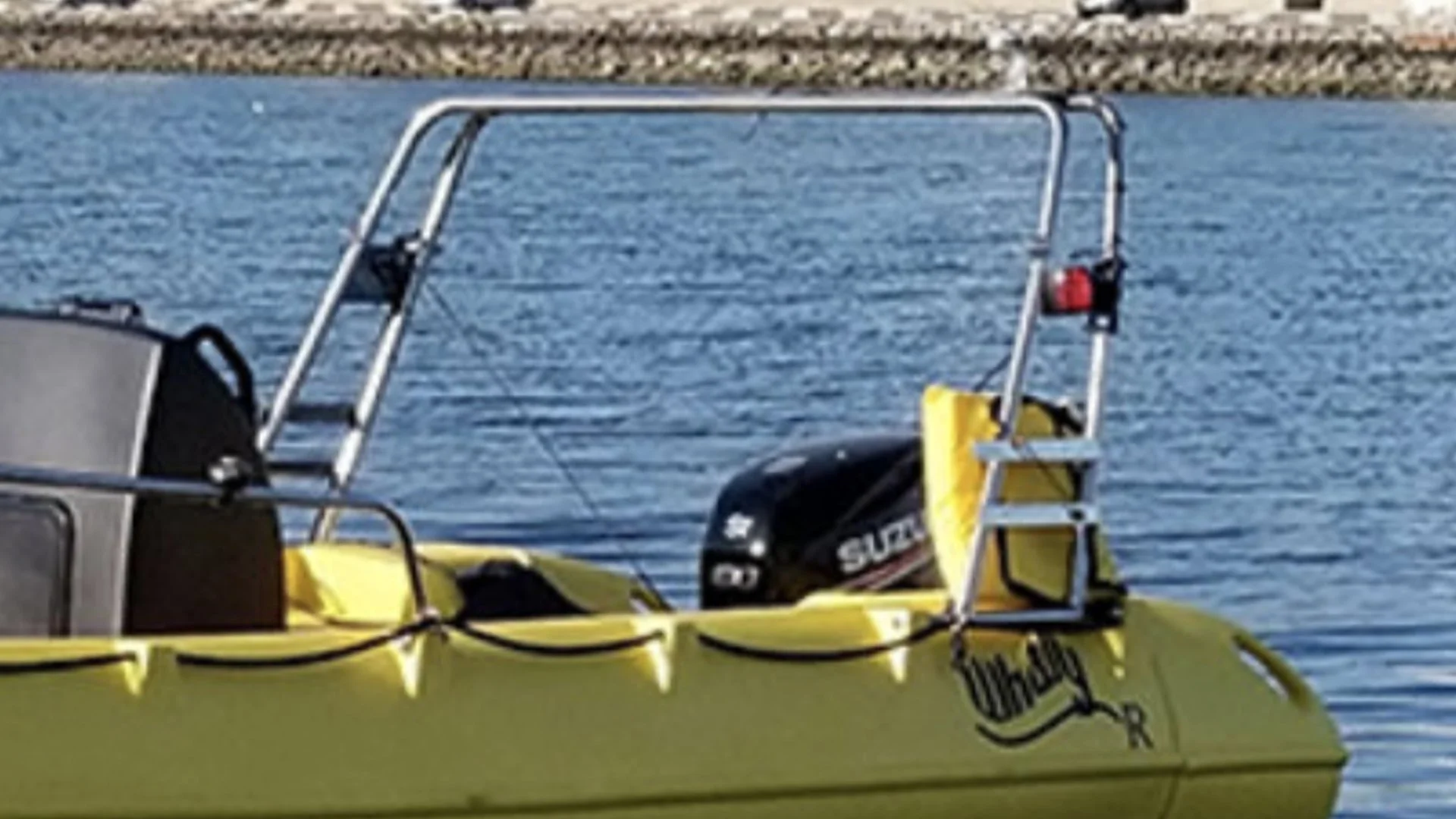 A yellow boat with a Suzuki outboard motor floating on a body of water, with a metal frame and ladder on the boat.