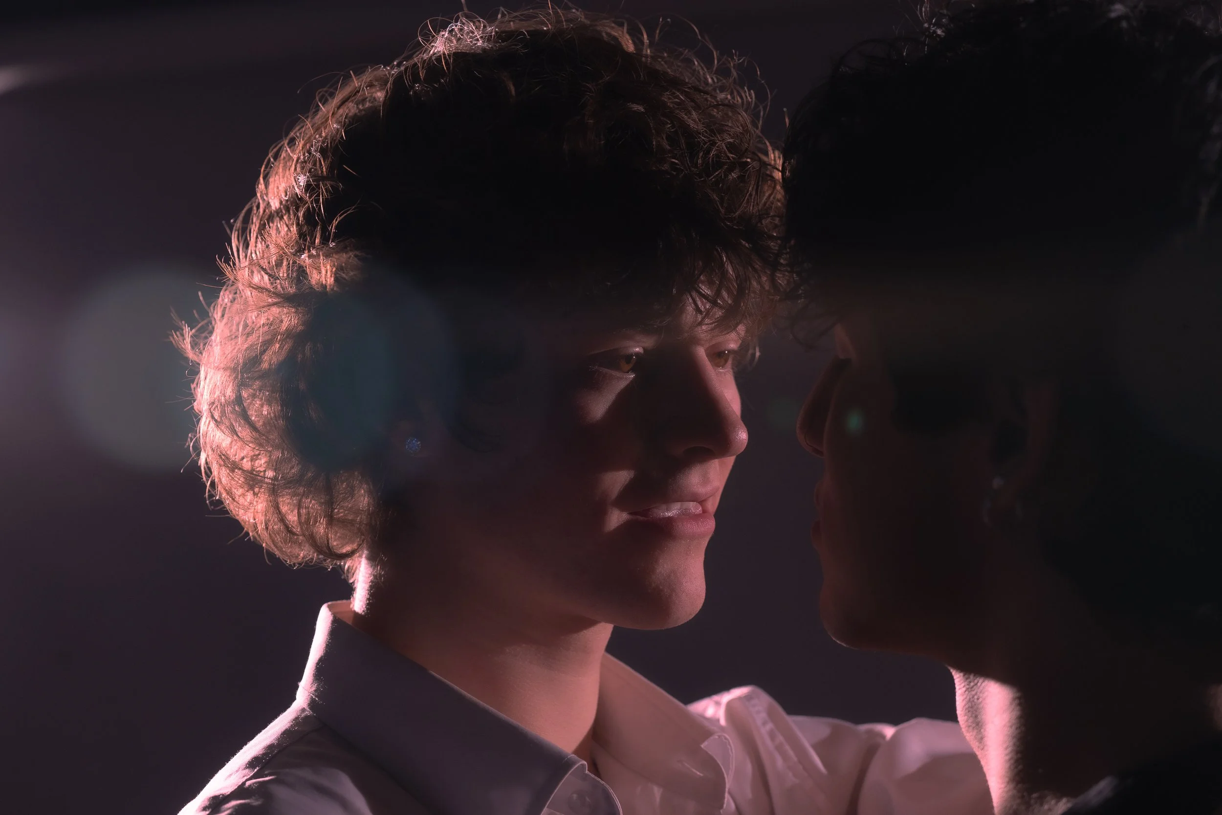 theatrical lighting of male couple, focused on one person