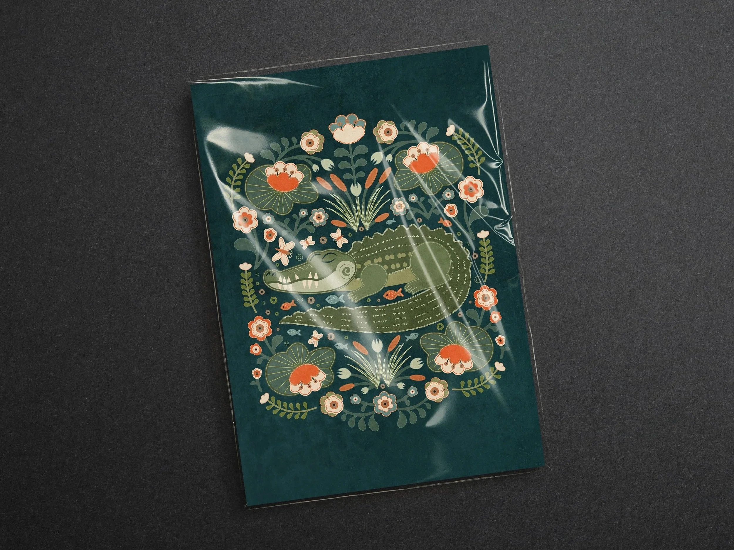 Folk art alligator illustration surrounded by decorative floral elements on a dark green background, shown as a printed art piece.