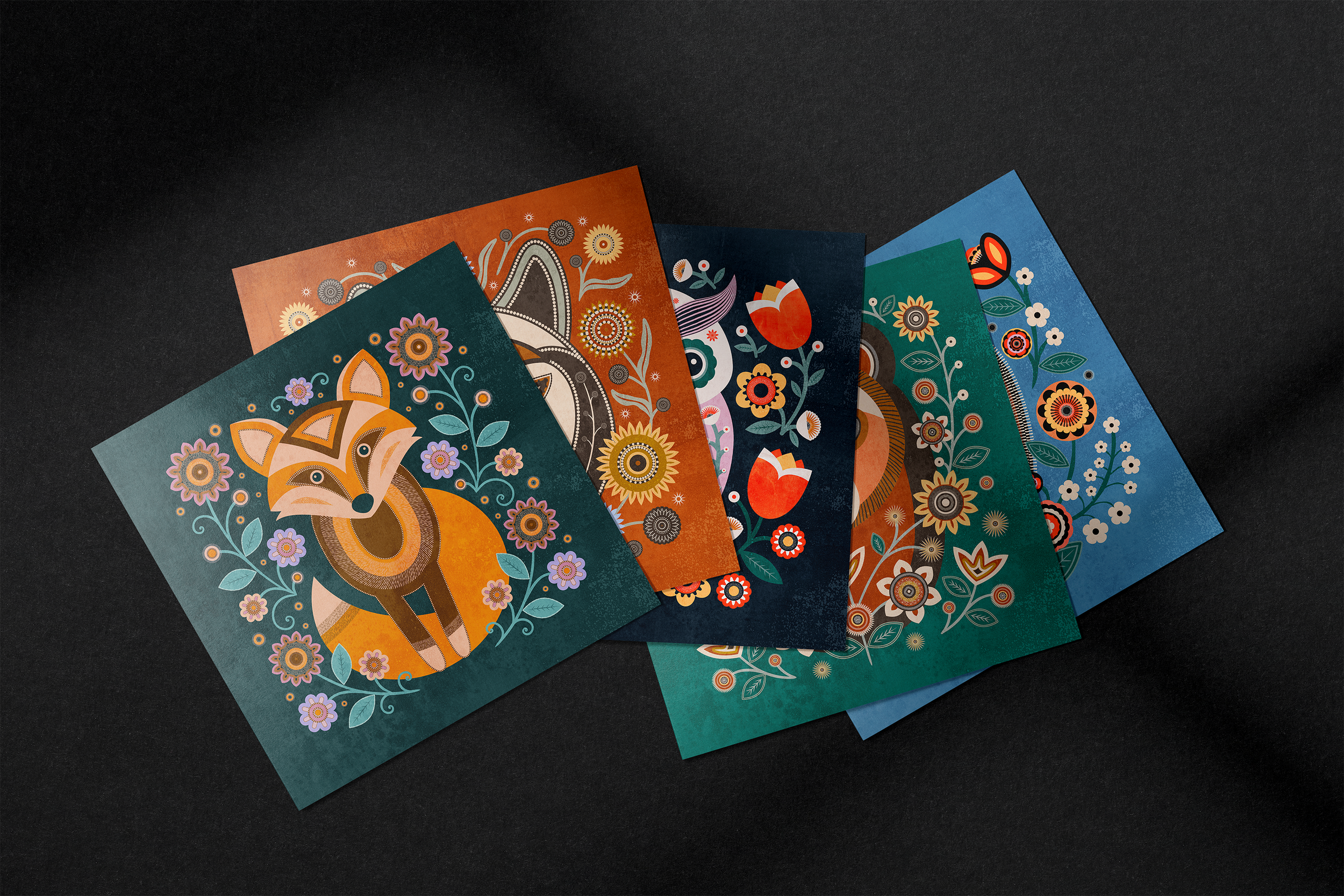 Square whimsical animal greeting cards with decorative floral folk-inspired illustrations, shown in a styled flat lay.