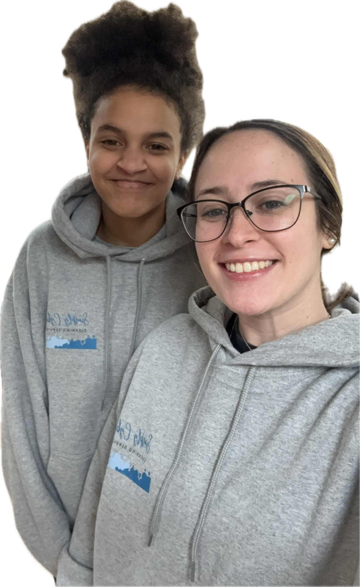 Two smiling women wearing matching light gray hoodies with a logo that reads "Simply Cybill" and an illustration of a shoreline with water and trees, standing close together.