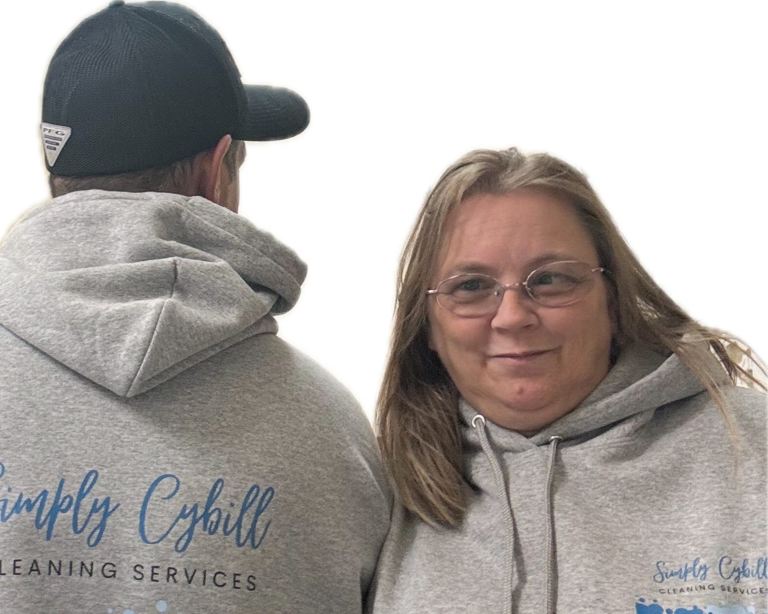 Two people wearing gray hoodies with the logo 'Simply Cybil Cleaning Services'; one man faces away, the woman faces toward the camera, smiling.