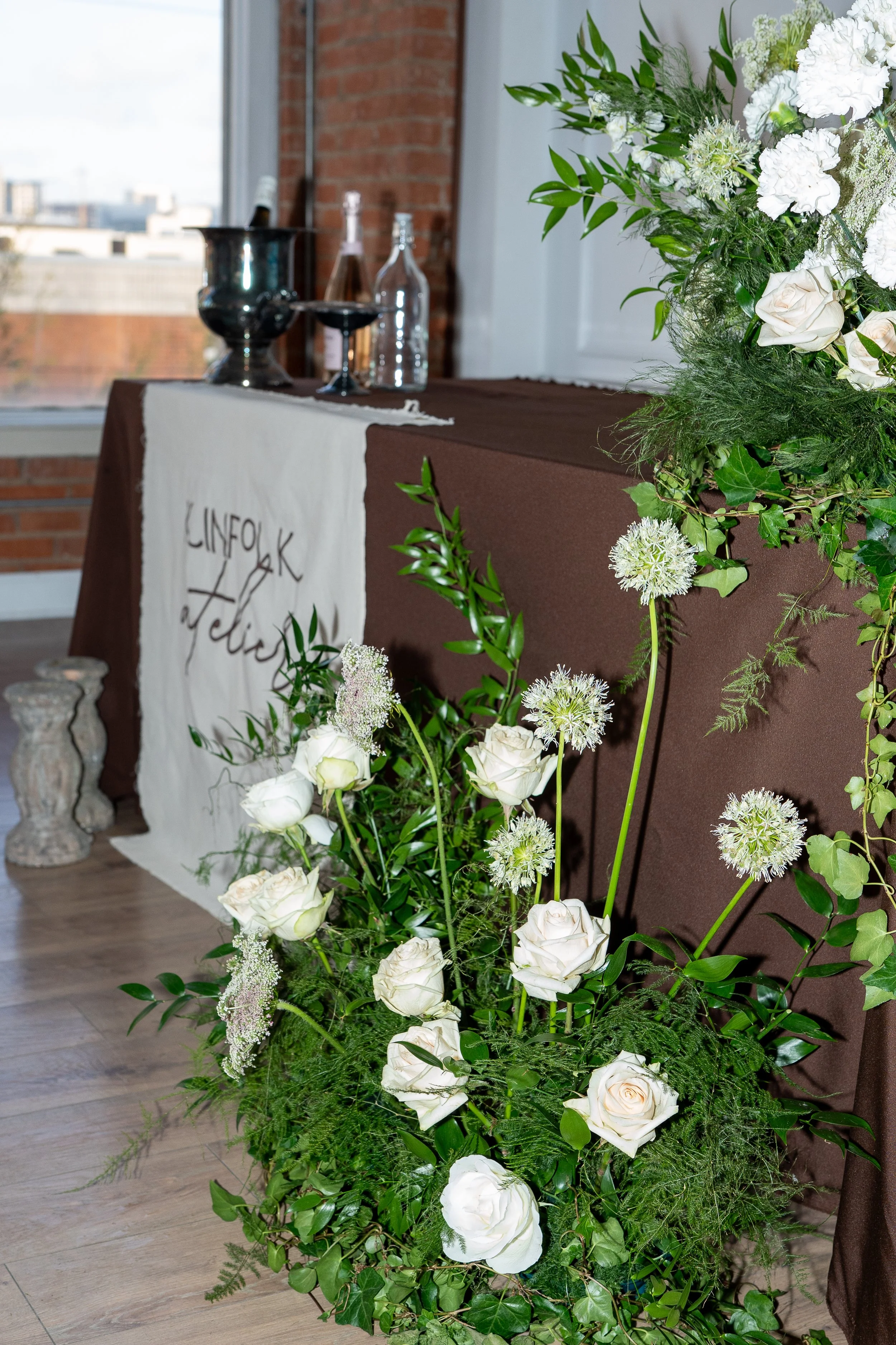 A floral arrangement with white roses and green foliage to showcase a simple, floral table installment.