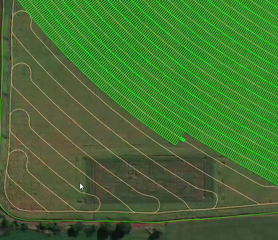 Aerial view of a large agricultural field divided into sections with contour lines, with a section marked by green grid overlay indicating a different zone or purpose.
