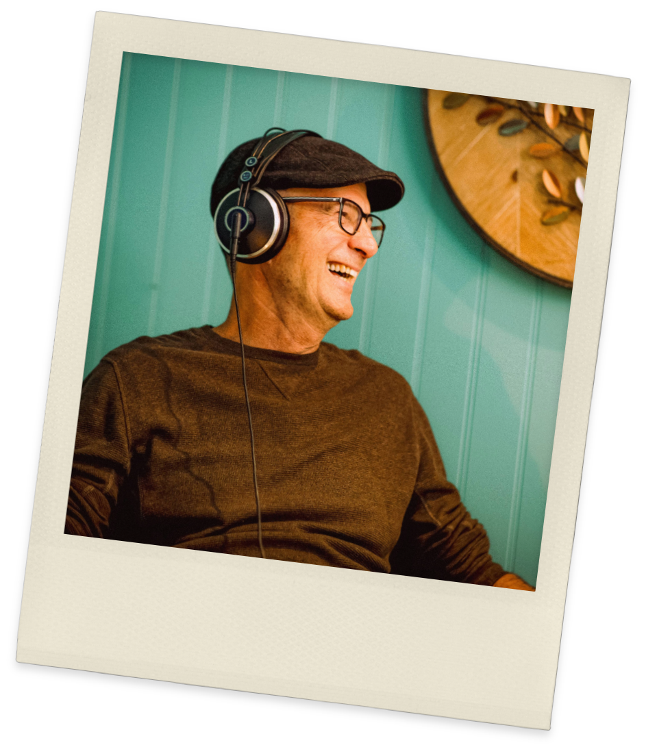 Vintage-style Polaroid shows man wearing cap laughing in front of blue walls