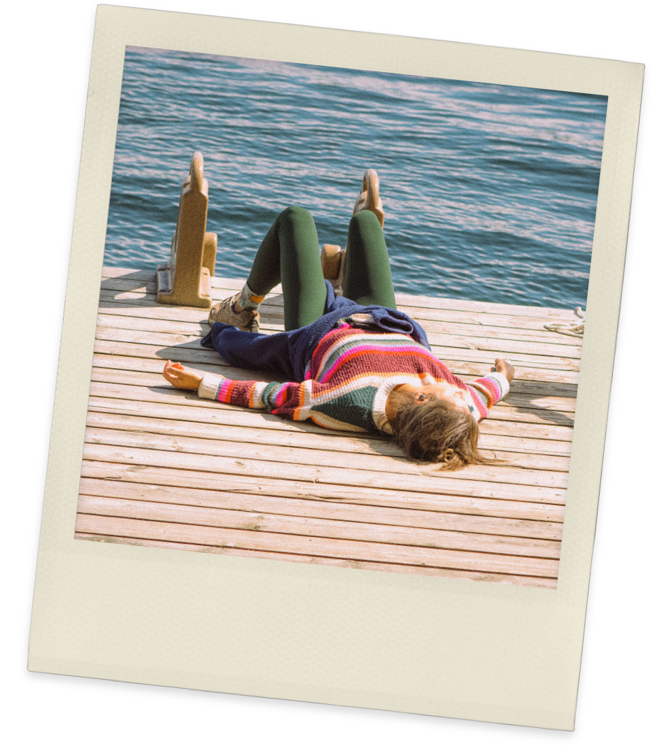 Vintage-style Polaroid shows woman lying on wooden dock