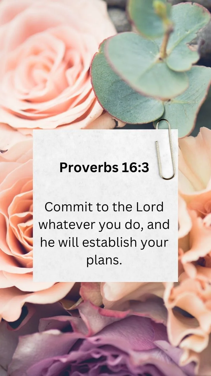 A floral background featuring pink roses, eucalyptus leaves, and purple flowers with a note attached that reads, 'Proverbs 16:3 Commit to the Lord whatever you do, and he will establish your plans,' clipped with a paperclip.