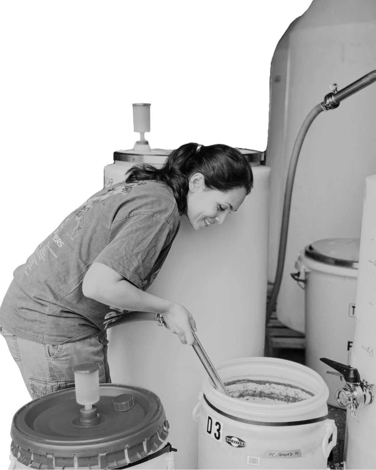 Photo of Therese Fessenden smiling and leaning over a large container of actively fermenting wine.