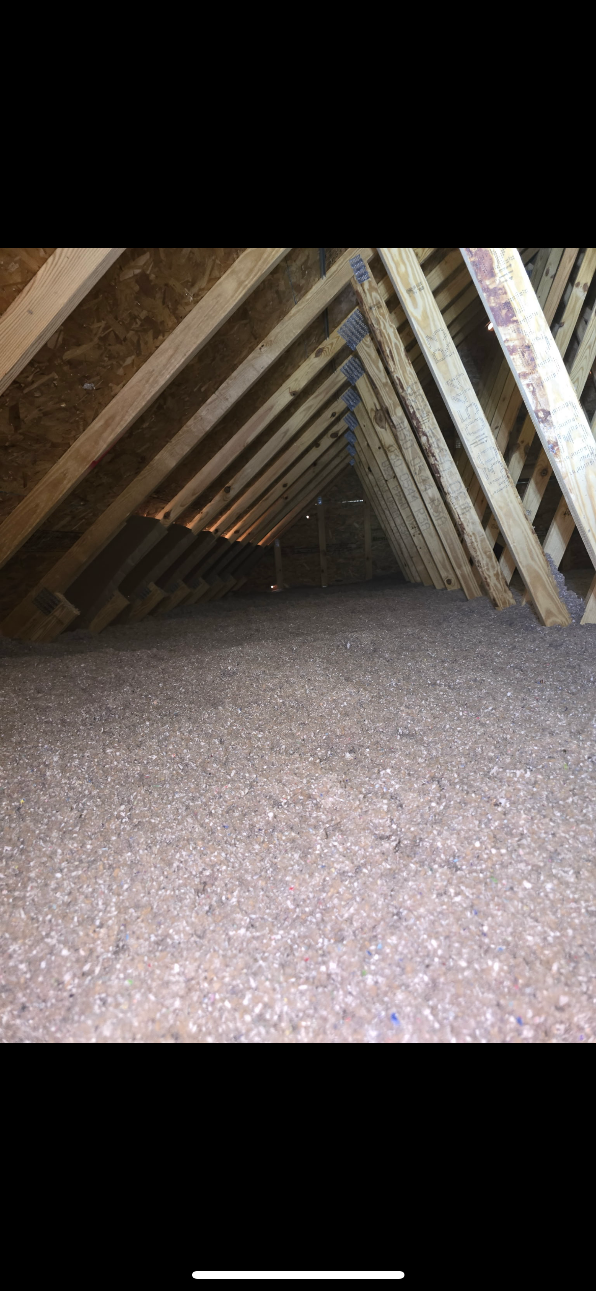 Attic with exposed wooden rafters and a gravel floor.