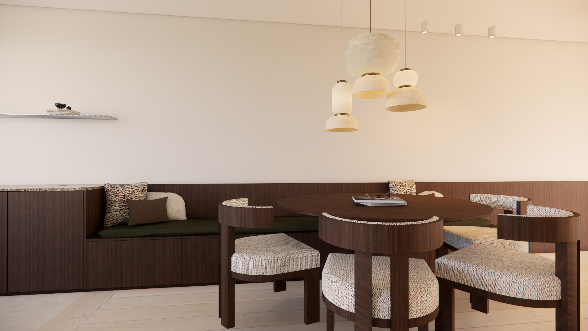 Interior of a dining room with a round wooden dining table surrounded by six upholstered chairs, and a built-in wood bench with cushions, wooden flooring, minimalist hanging light fixtures, and a white wall with a floating shelf.