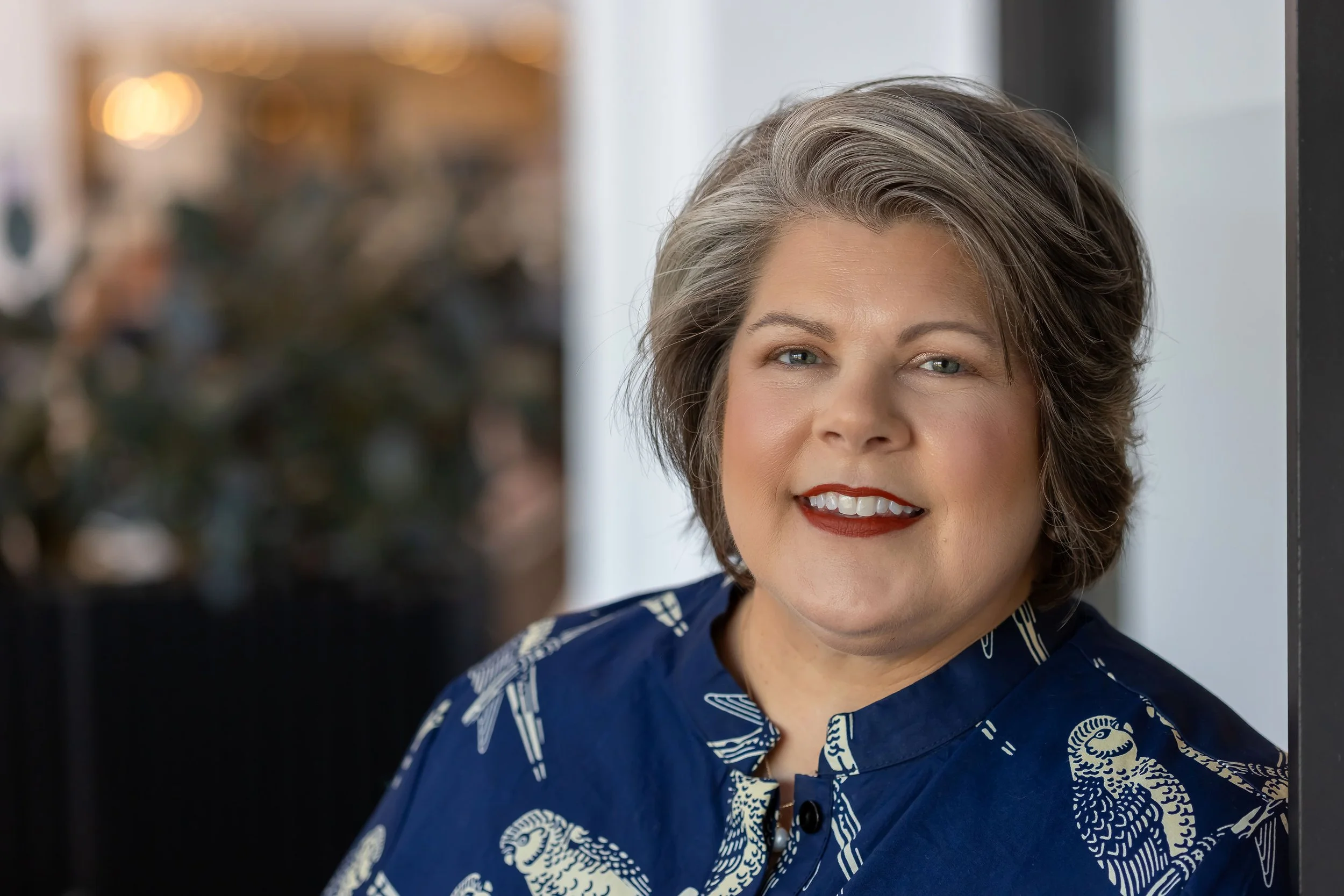 image of white middle aged woman wearing a blue dress with birds on it. She is a large woman who is looking at the camera.