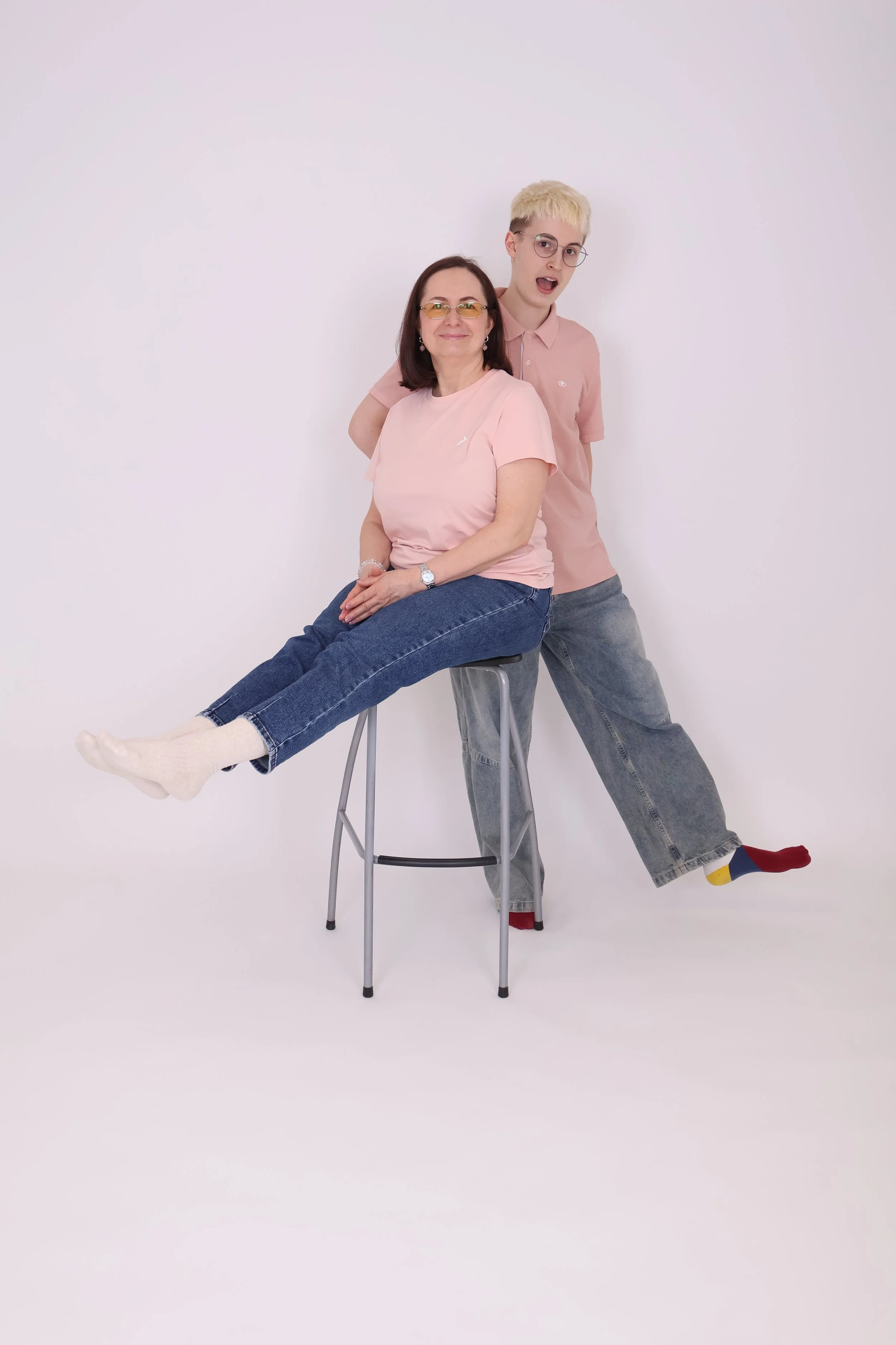 Äiti ja lapsi poseeraavat värikkäissä vaatteissa valkoisella taustalla.