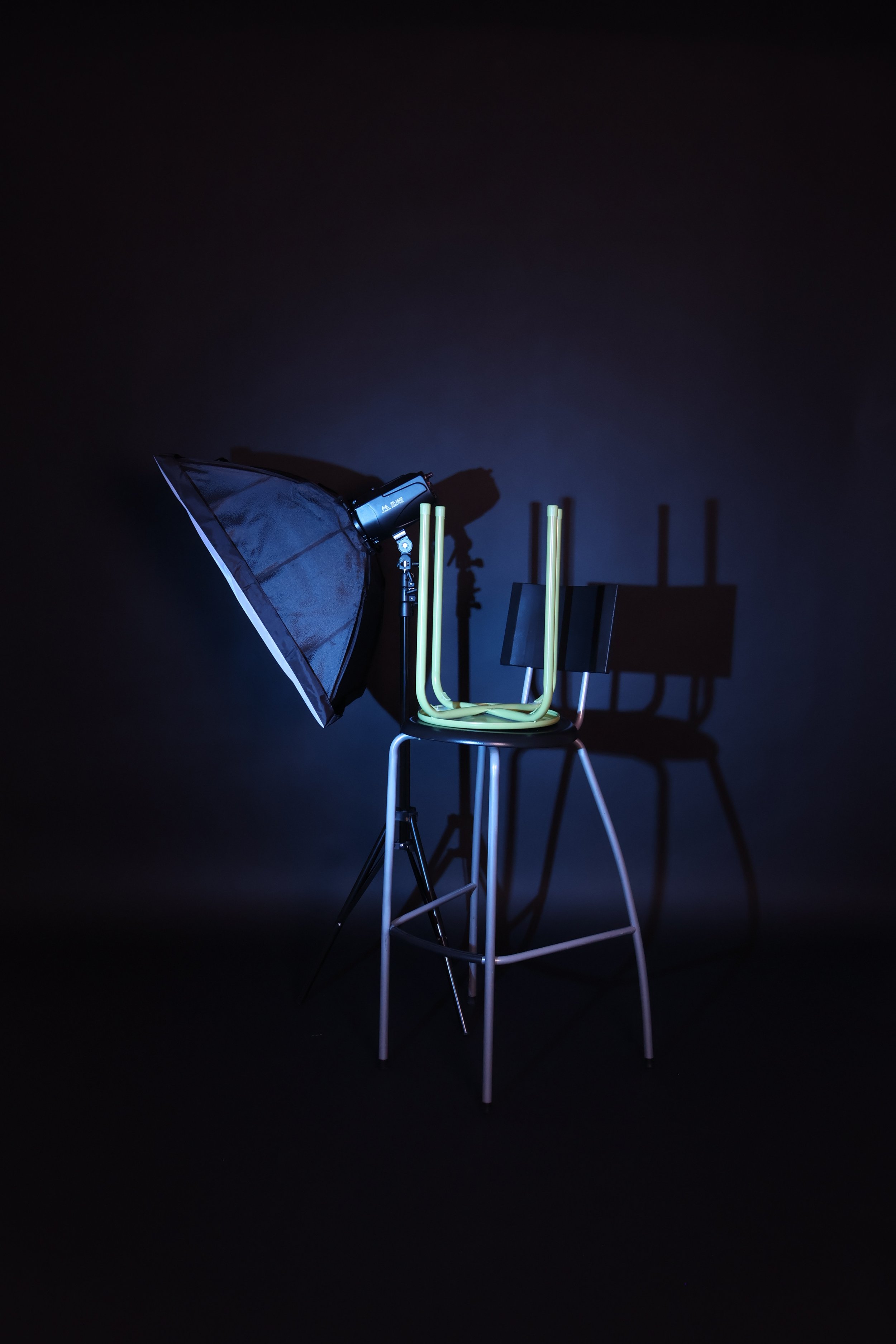 Valonheitin ja tuoli valaistussa studio-ympäristössä, varjo taustalla.