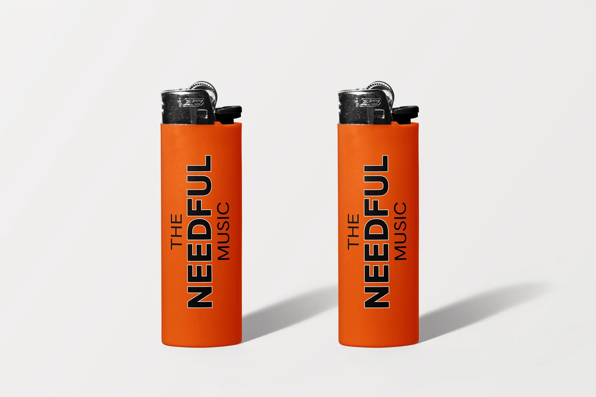 Two of the needful lighters standing up, bright orange colour with logo