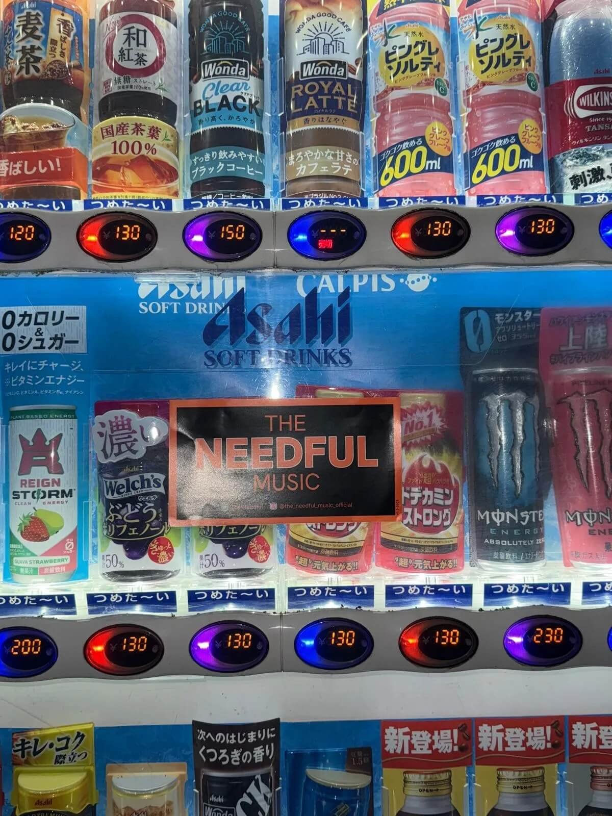 A vending machine with various beverages, including canned coffee, energy drinks, and soft drinks, with digital price displays.
