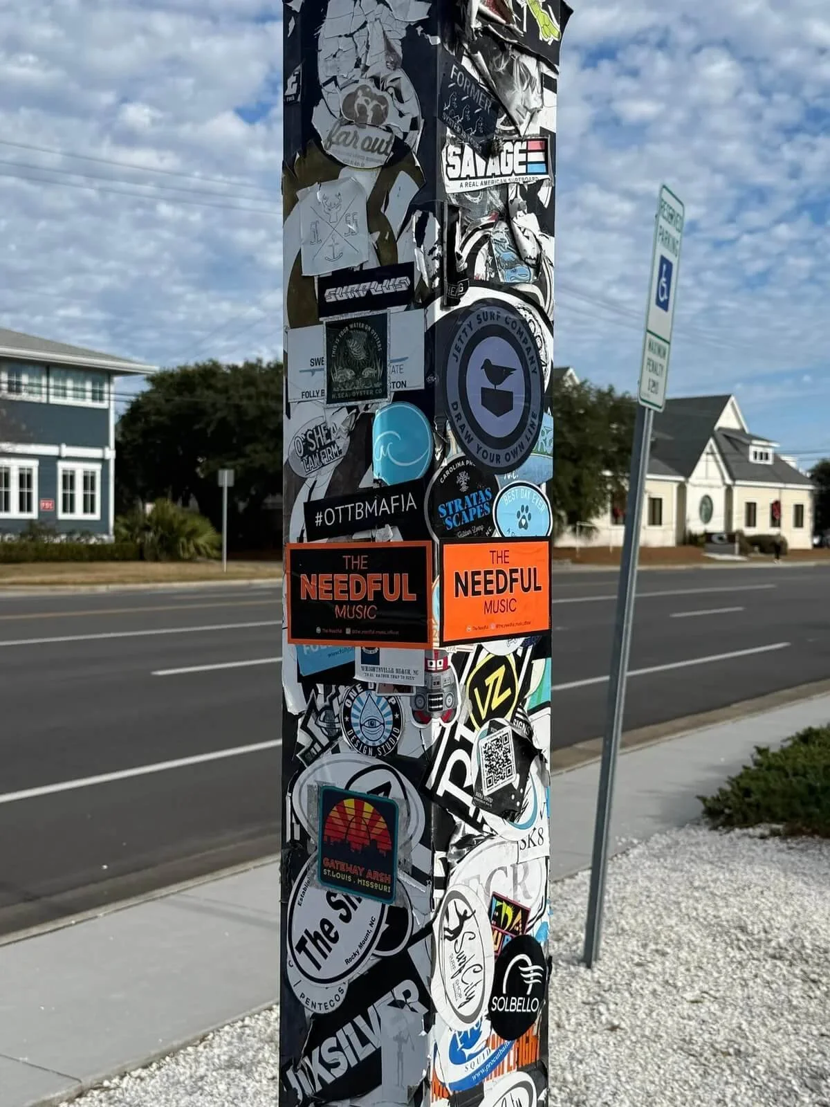 A street pole covered in various stickers and decals of different shapes, sizes, and colors.