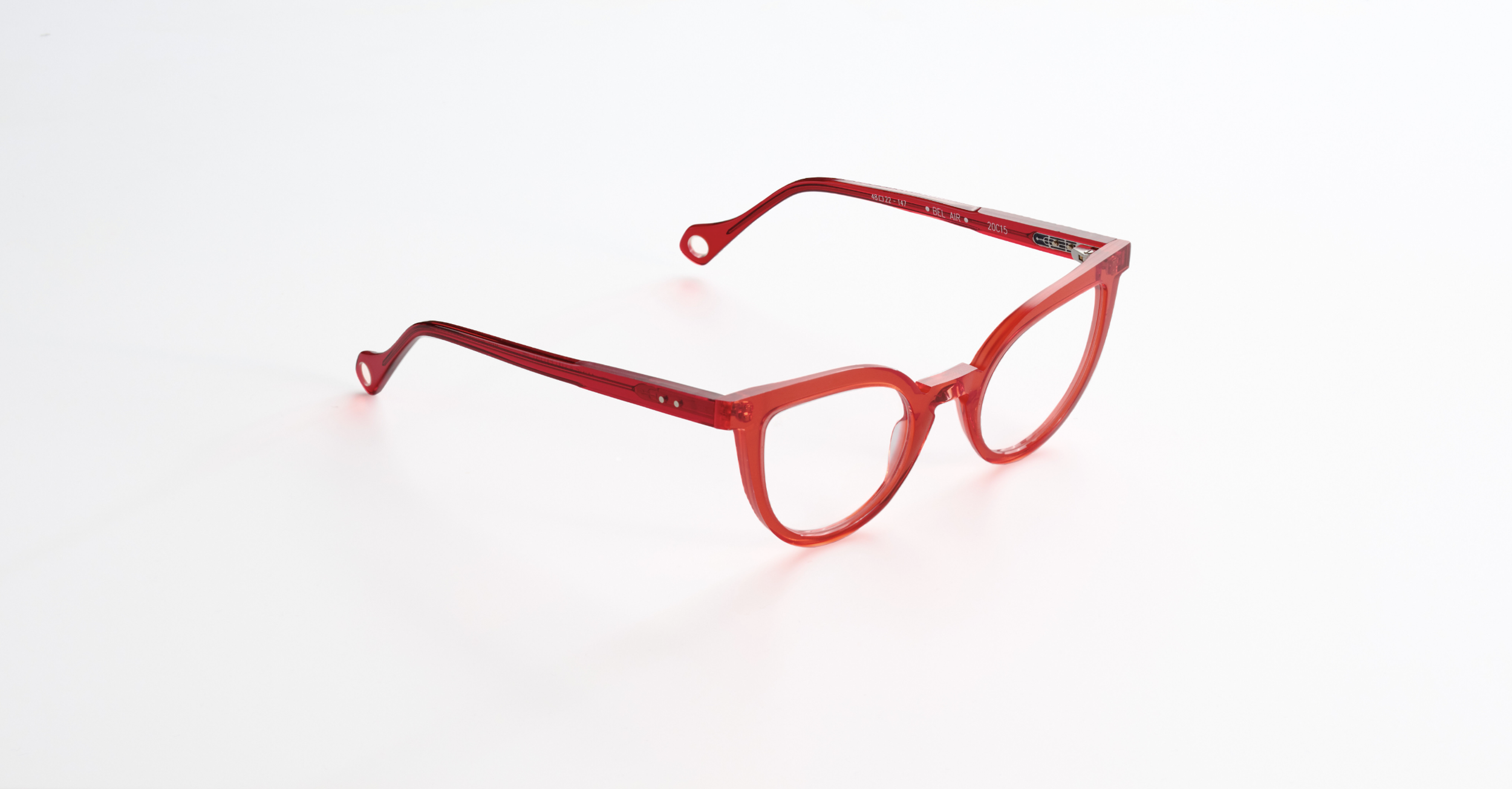 A pair of Anne and Valentin red eyeglasses with a plastic frame and clear lenses on a white background.