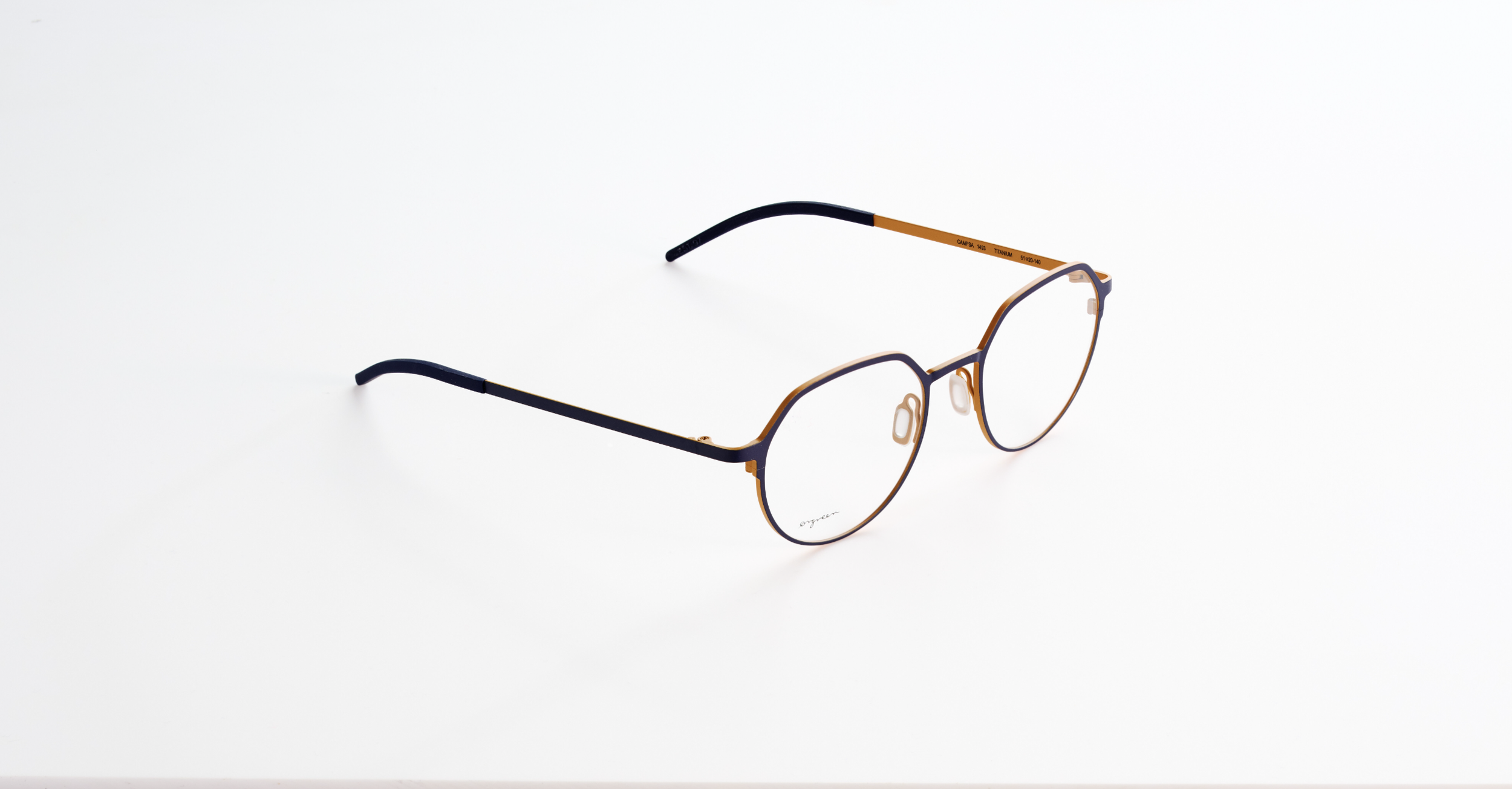 A pair of Orgreen eyeglasses with a thin, black and orange frame resting on a white surface.
