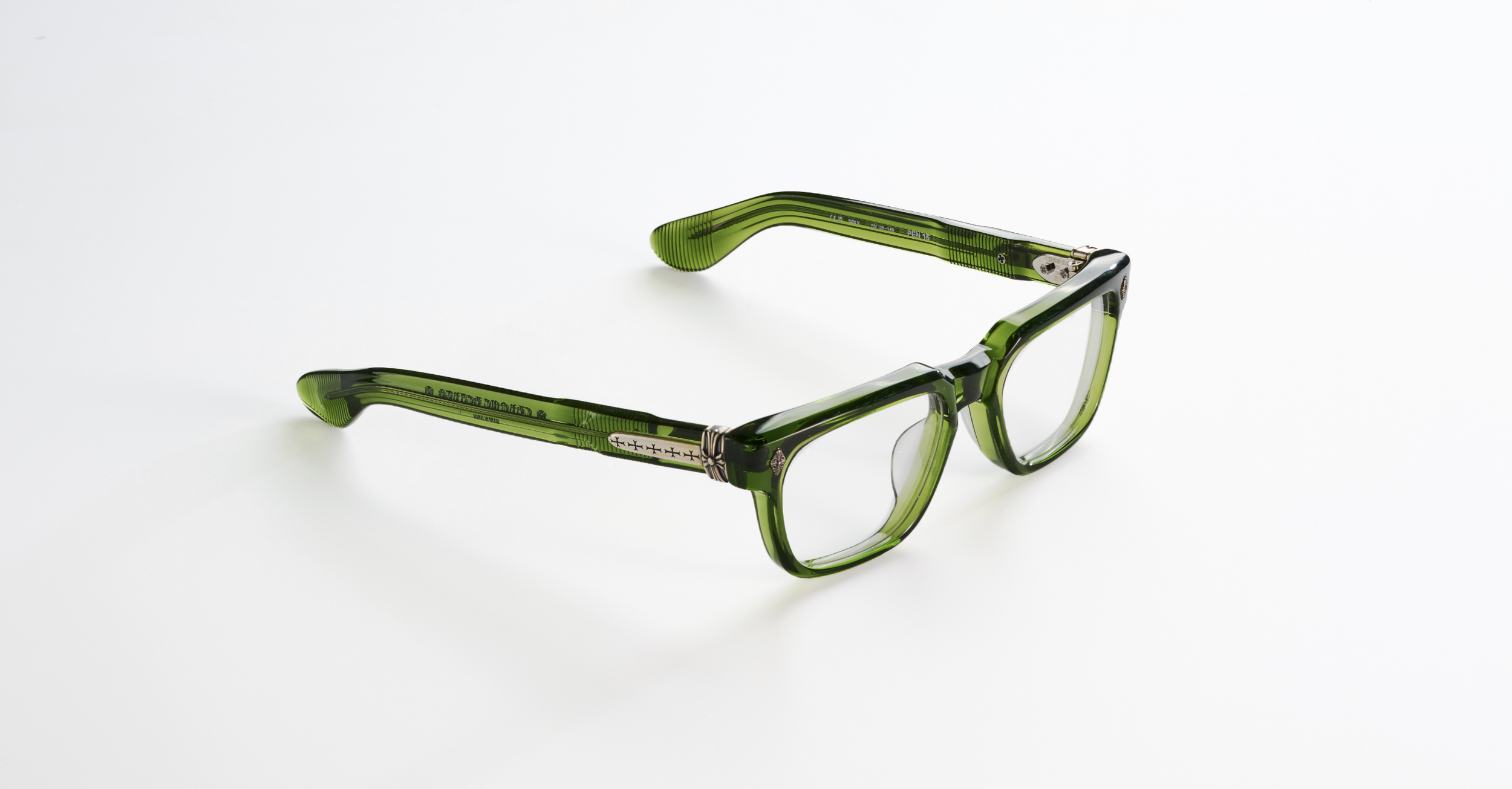 A pair of Chrome hearts green eyeglasses with clear lenses lying on a white surface.