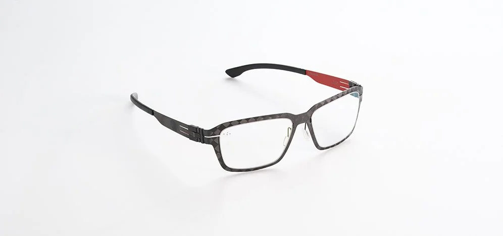 A pair of Ici Berlin eyeglasses with black patterned frame and red accents on the temple, on a white background.