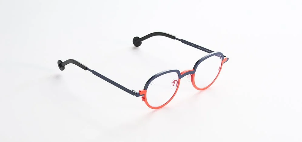 A pair of Theo eyeglasses with black and red frames on a white background.