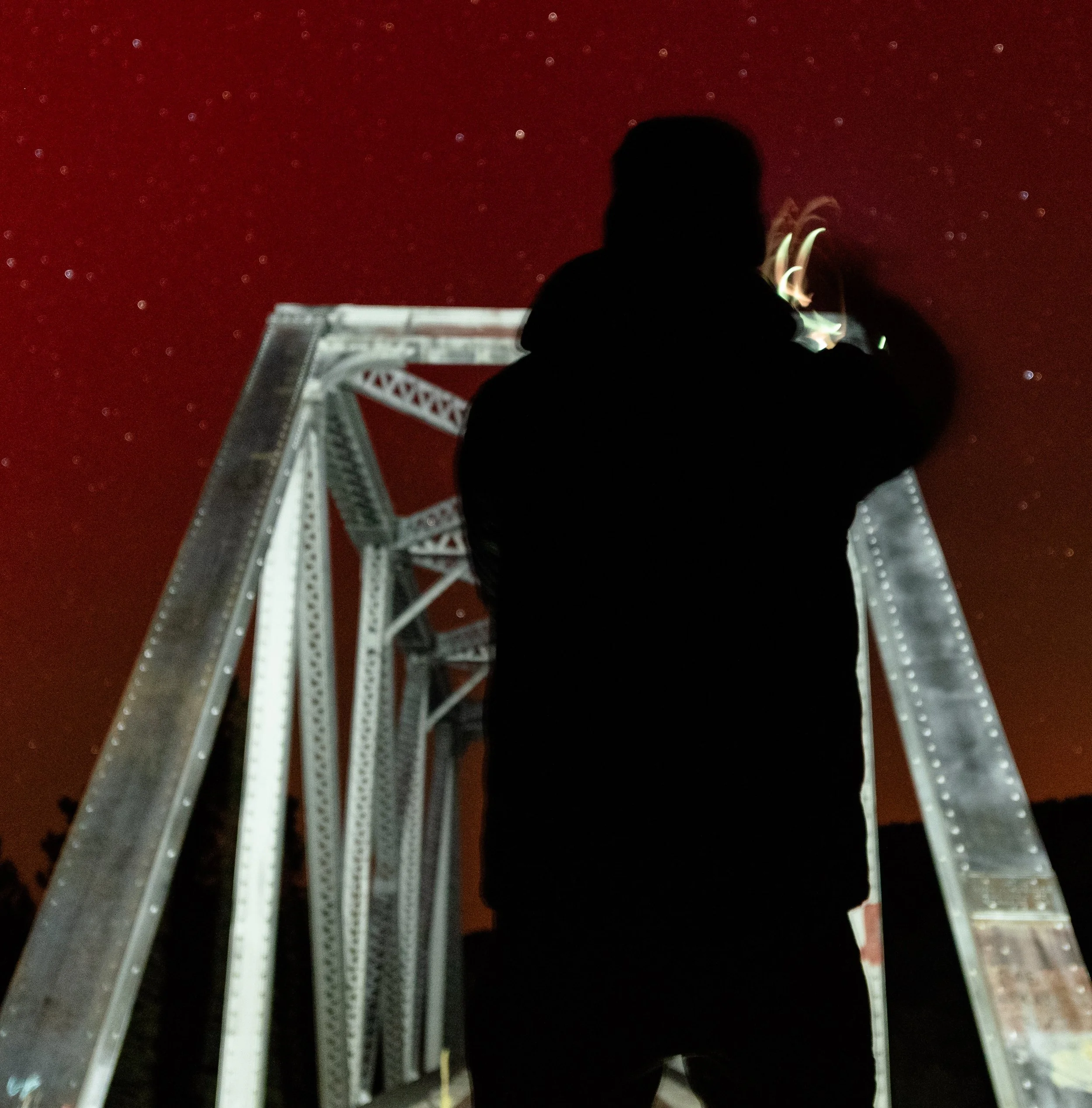 Silhouette of Eric in front of BV Rail Bridge during 11/11/2025 Northern Lights