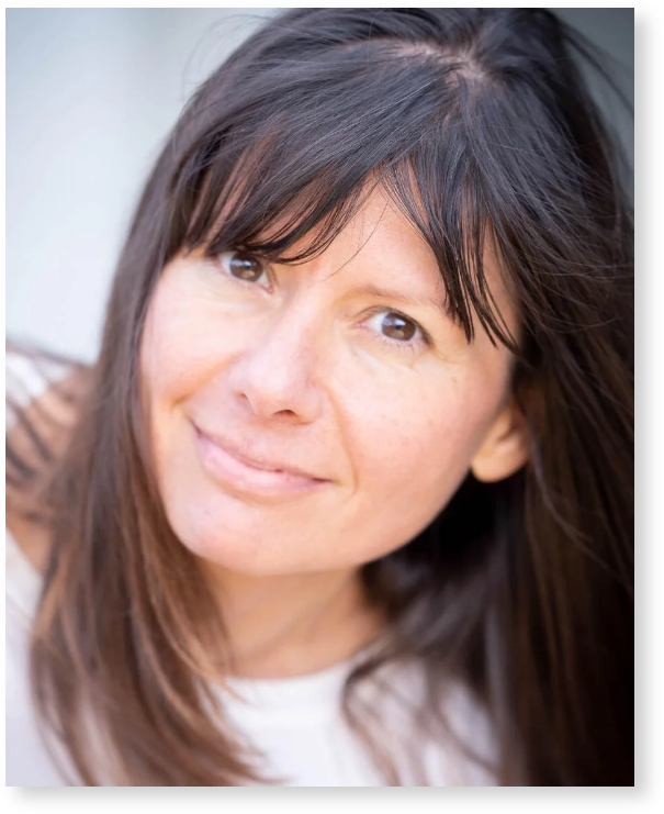 Close-up portrait of a woman with brown hair and brown eyes, smiling softly at the camera.
