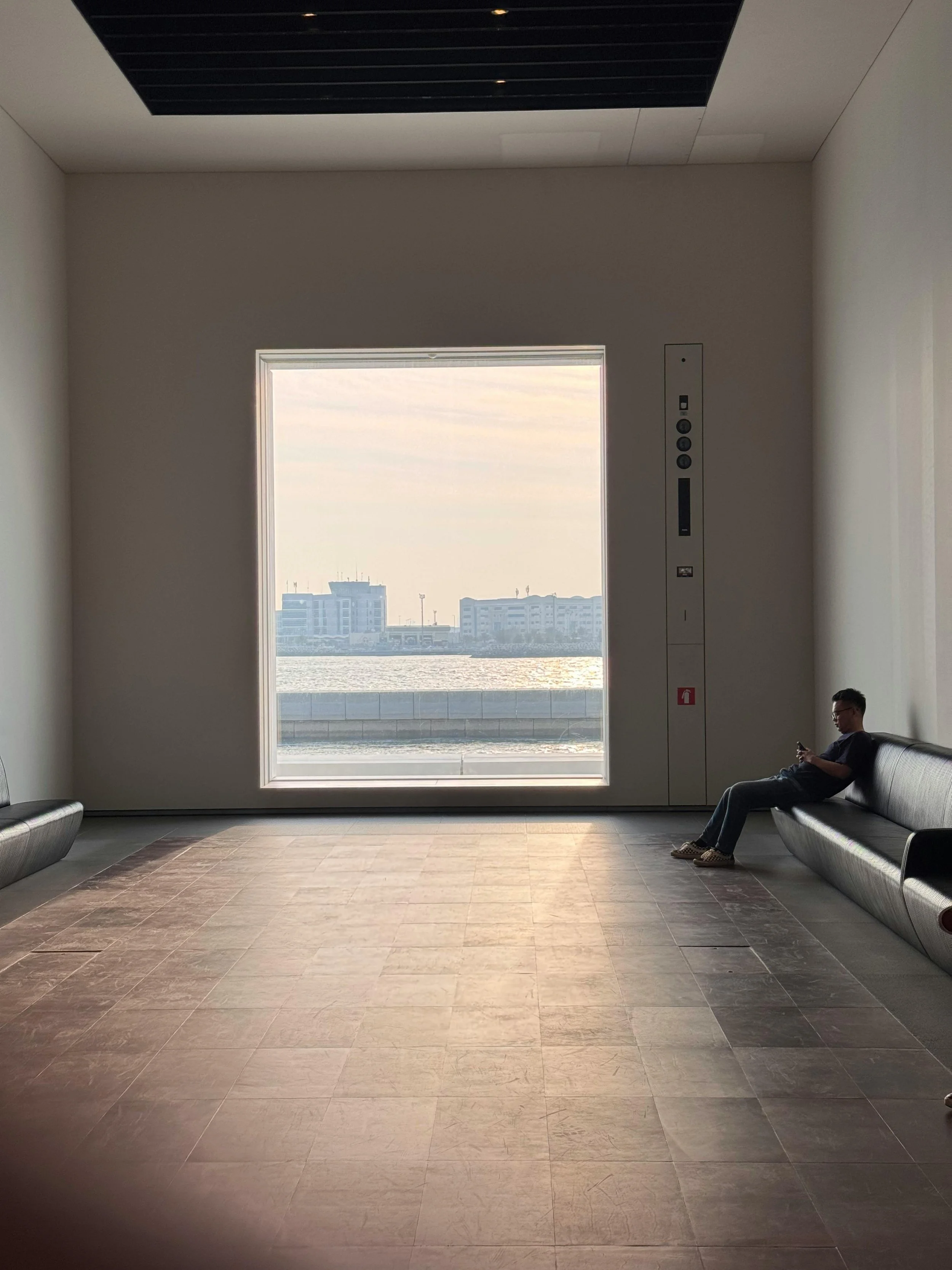 a man slumps down on a couch in a dreary room, staring mindlessly at his phone
