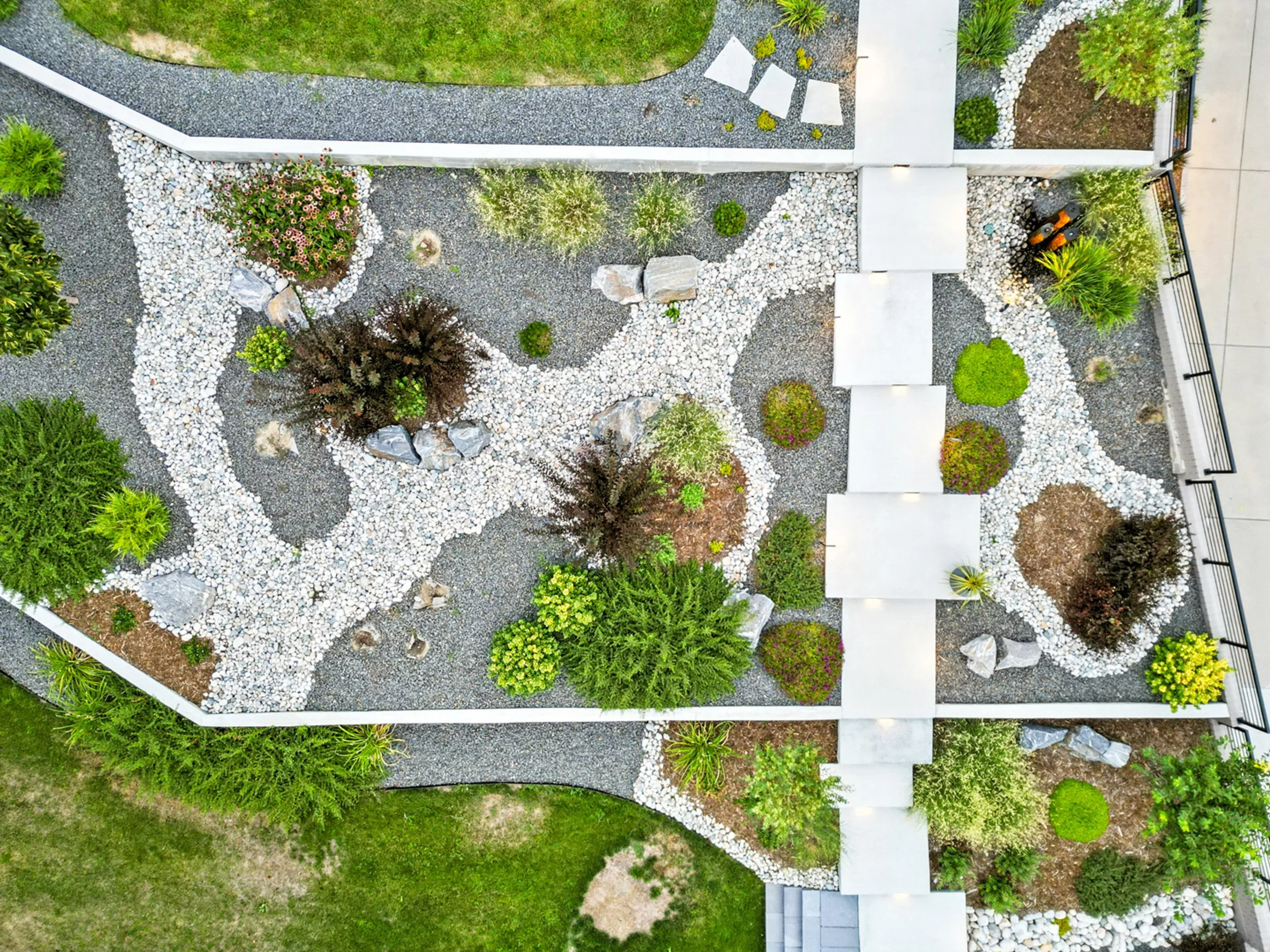 Aerial view of a landscaped garden with stone pathways, bushes, and trees.