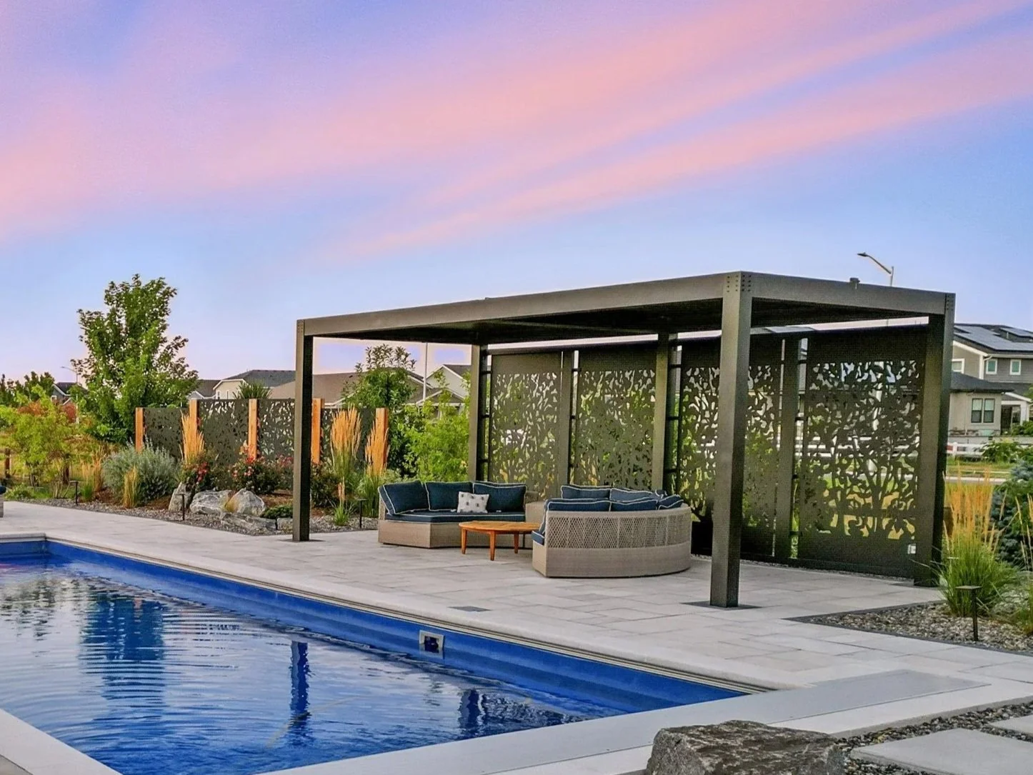 A backyard pool area with a seating pavilion and landscaped garden.