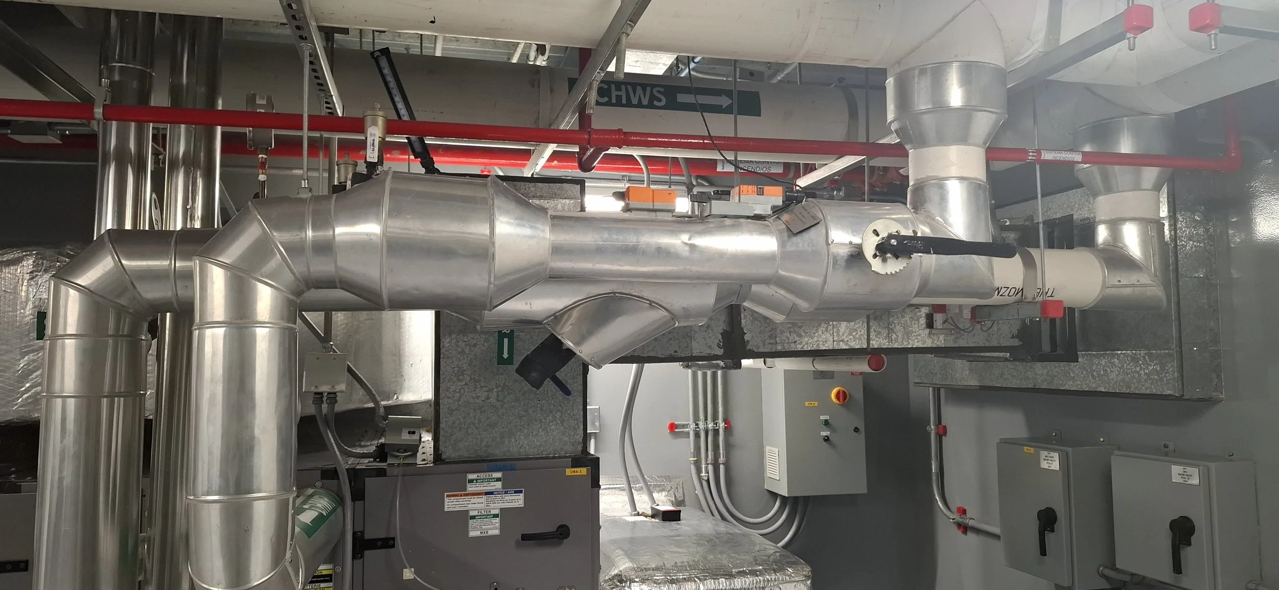 Sistema de tuberías metálicas en un espacio industrial, con válvulas, controles y señalización.