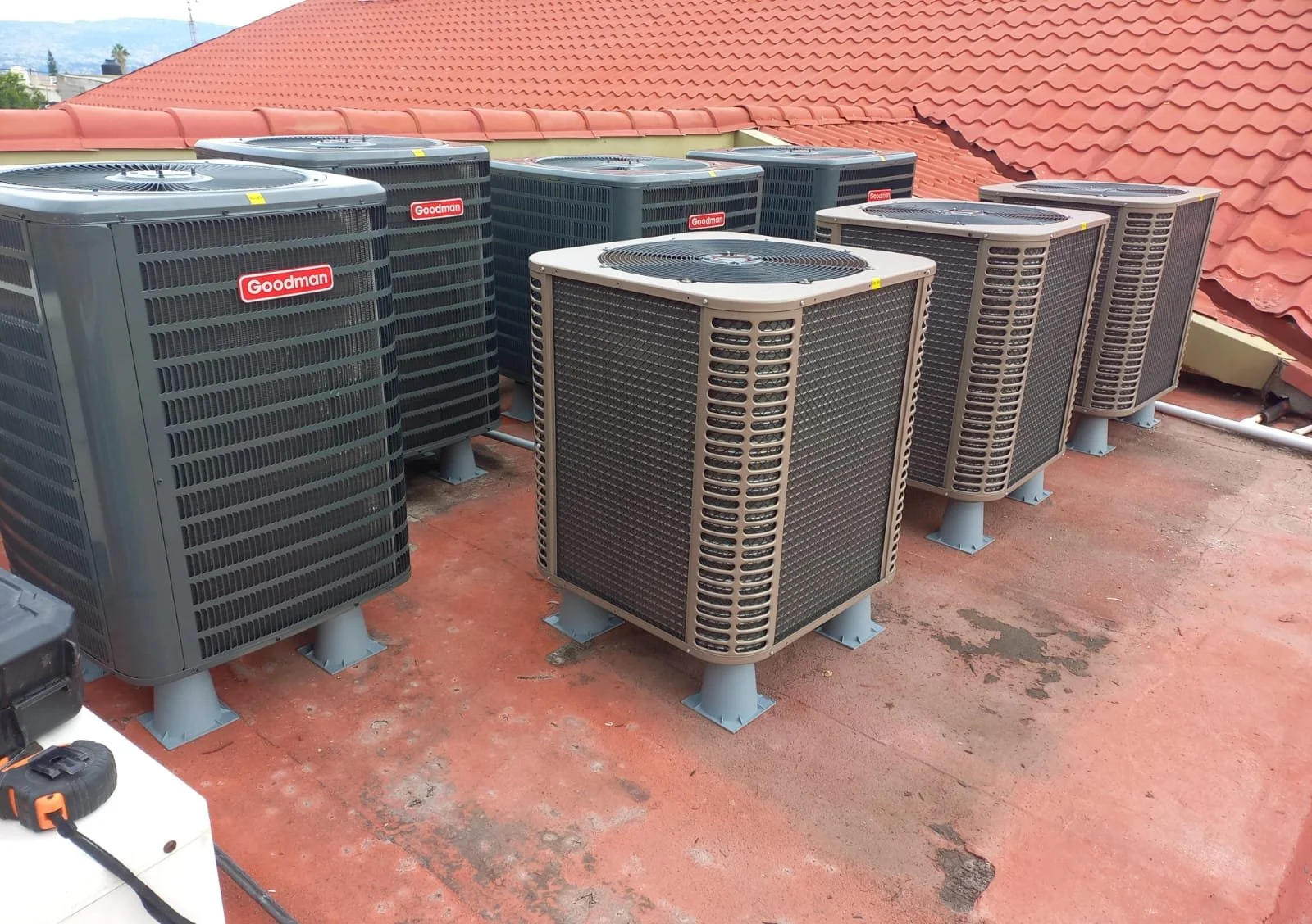 Diversos unidades de aire acondicionado Goodman instaladas en una azotea con techo de tejas rojas.