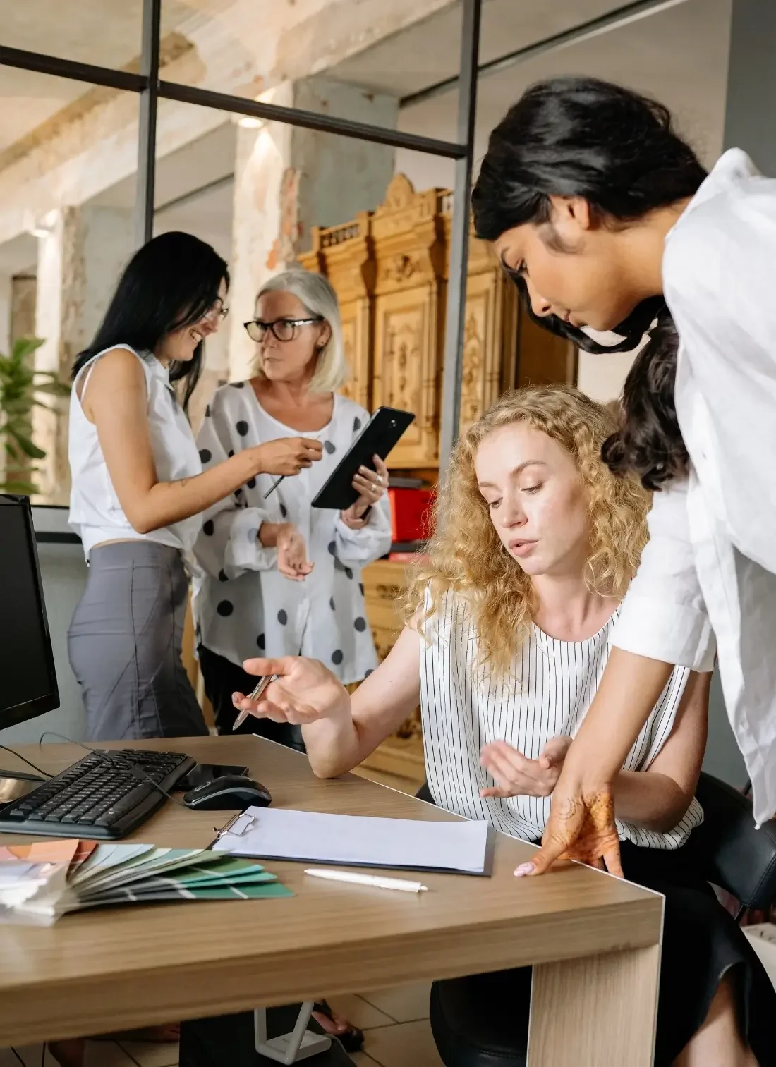 Group of 4 female co-workers collaborating on a project in the office