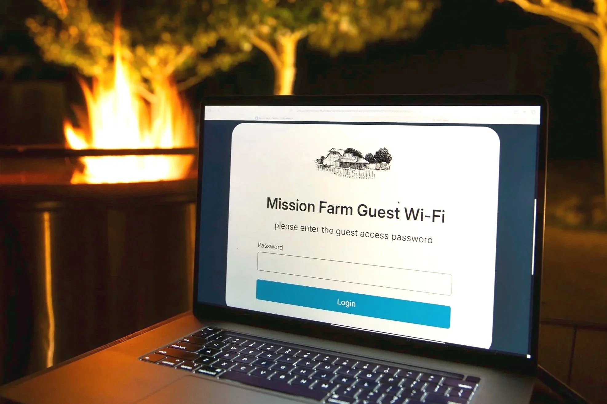 Laptop screen displaying a Wi-Fi login page for Mission Farm Guest Wi-Fi, with a drawing of farm buildings at the top, set outdoors at night with a fire in the background.