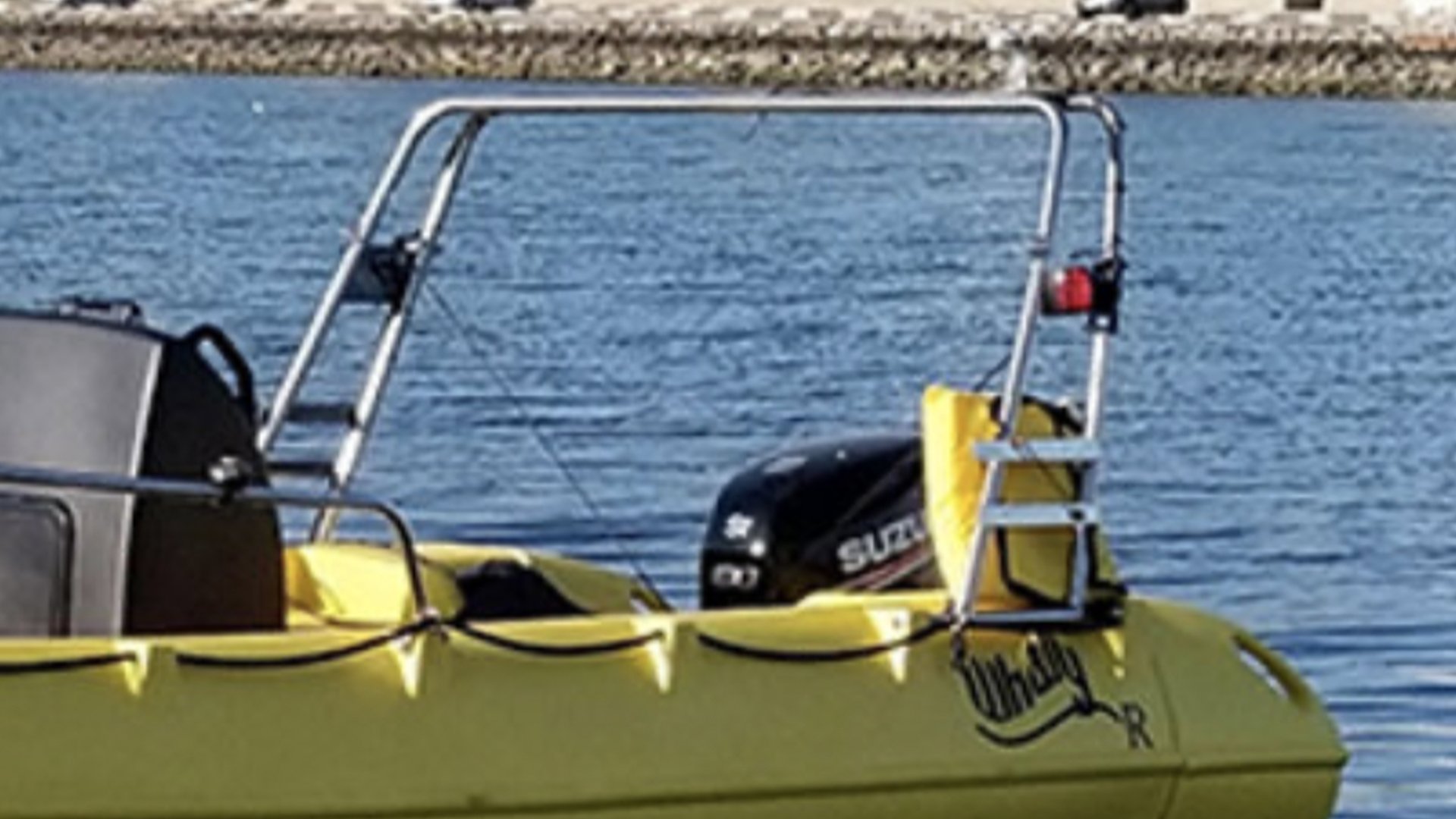 A yellow boat with a Suzuki outboard motor floating on a body of water, with a metal frame and ladder on the boat.