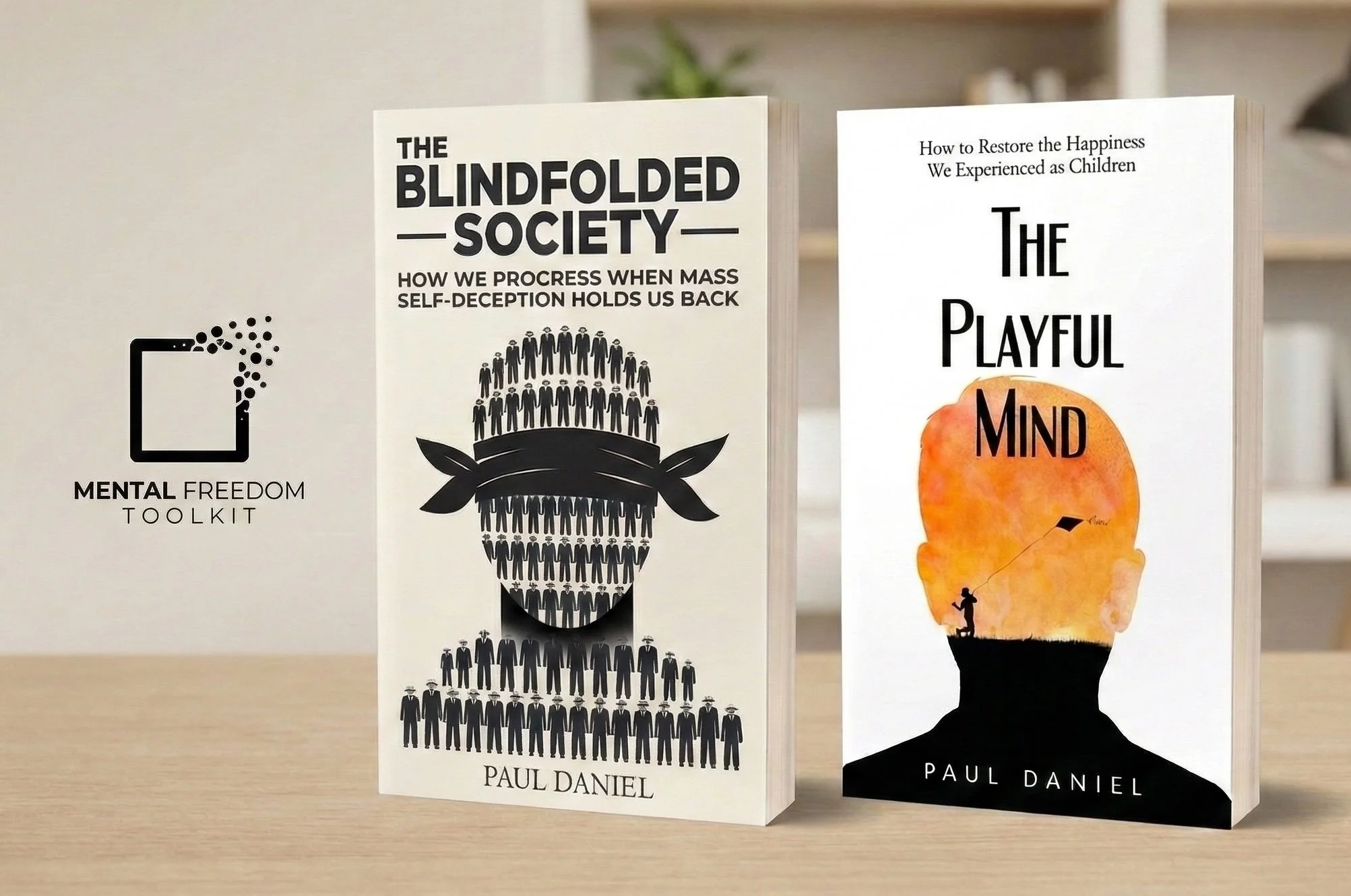 The Mental Freedom Toolkit book series by author Paul Daniel, featuring professional mockups of 'The Blindfolded Society' and 'The Playful Mind' standing on a light wooden table.