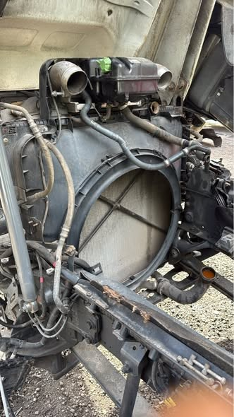 Engine compartment of a vehicle with some components removed, exposing internal parts and hoses.