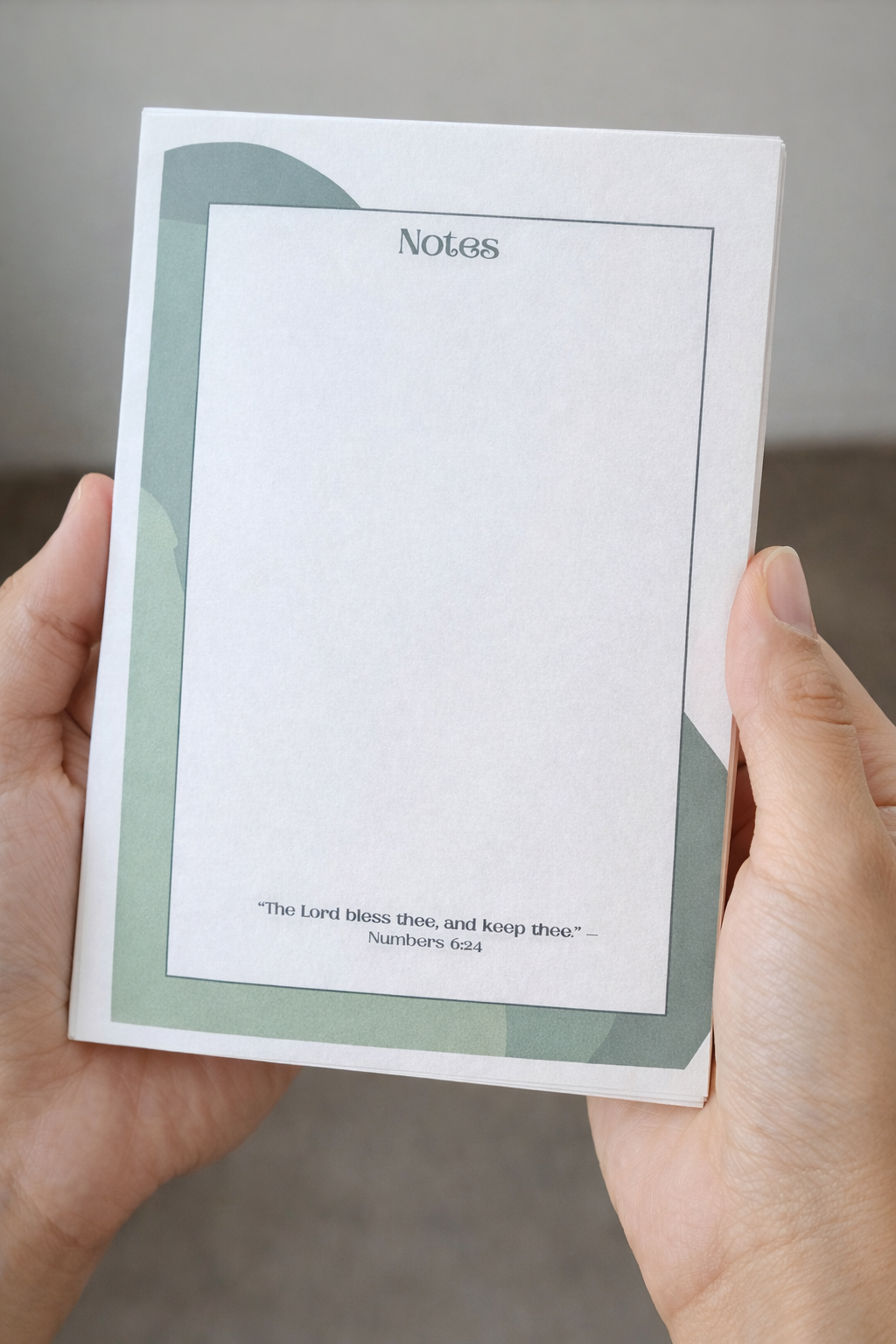 Hands holding a 5x7 Christian notepad with green accents and Numbers 6:24 printed at the bottom