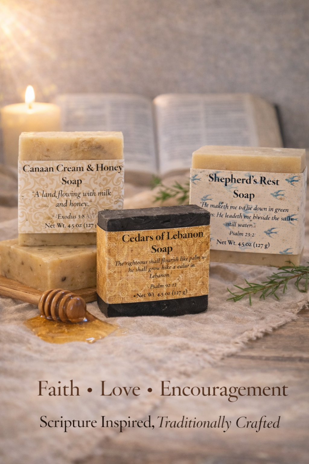 Three bars of handcrafted soap labeled Canaan Cream & Honey, Shepherd's Rest, and Cedars of Lebanon placed on a cloth with a honey dipper and a candle in the background. Open book and greenery decor.